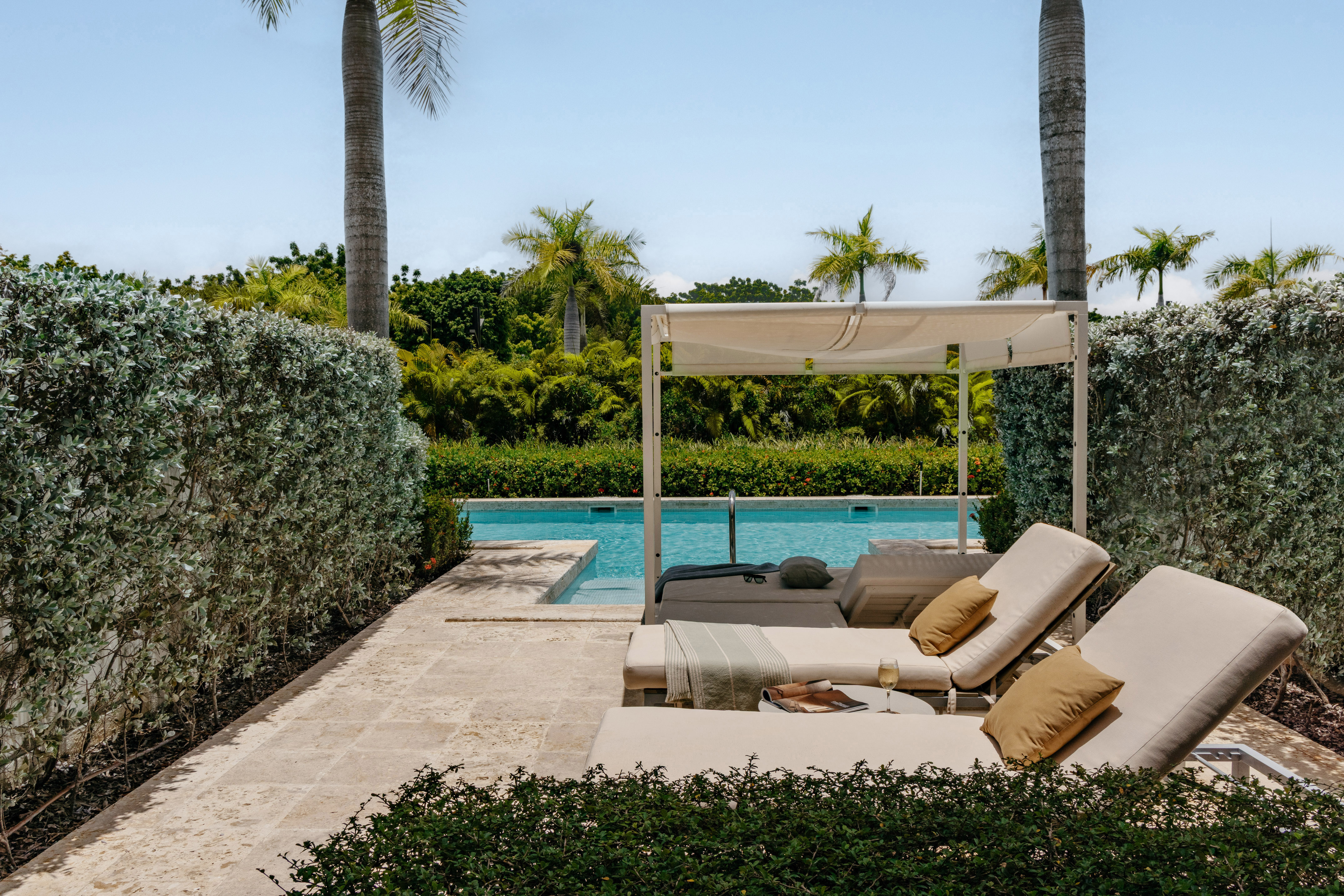 Luxury pool deck with cabana, lounge chairs, and tropical landscaping.