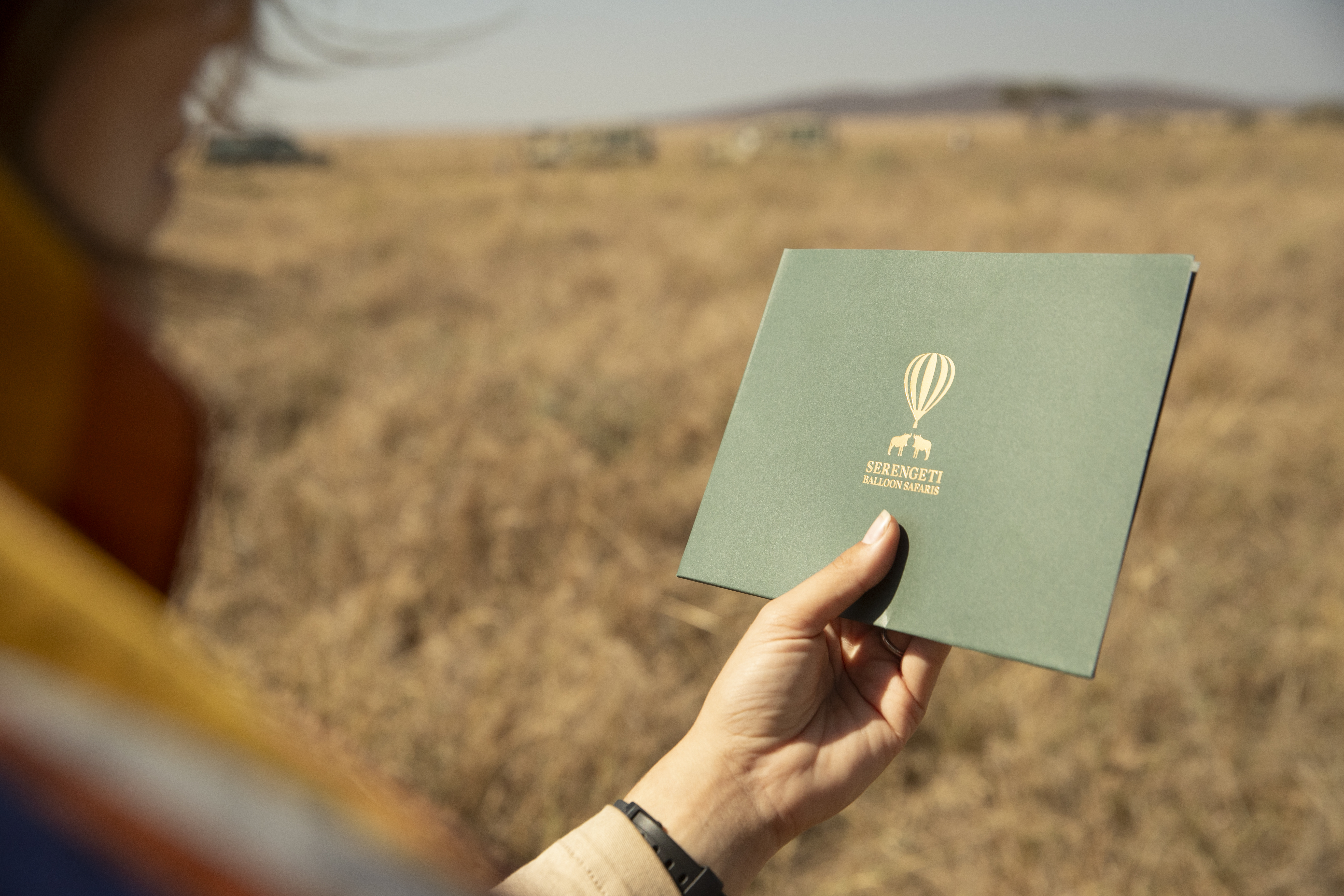 a person holding a green square with a hot air balloon logo
