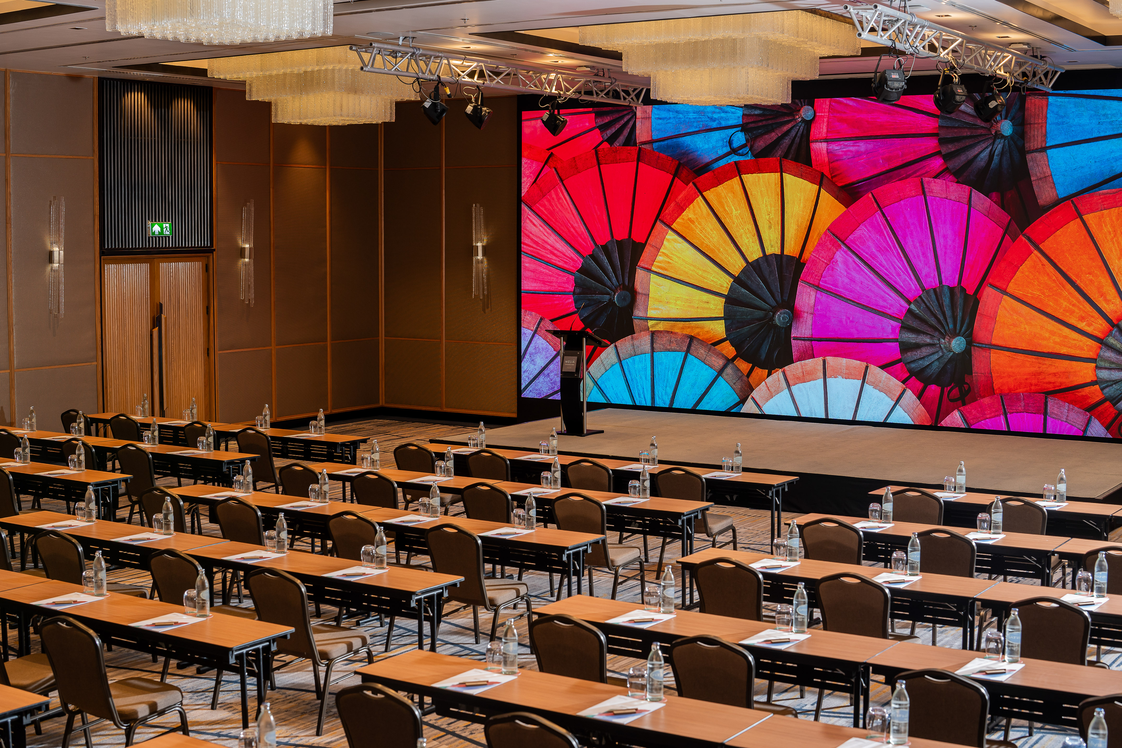 Conference room with stage, colorful umbrella LED screen, and event seating.