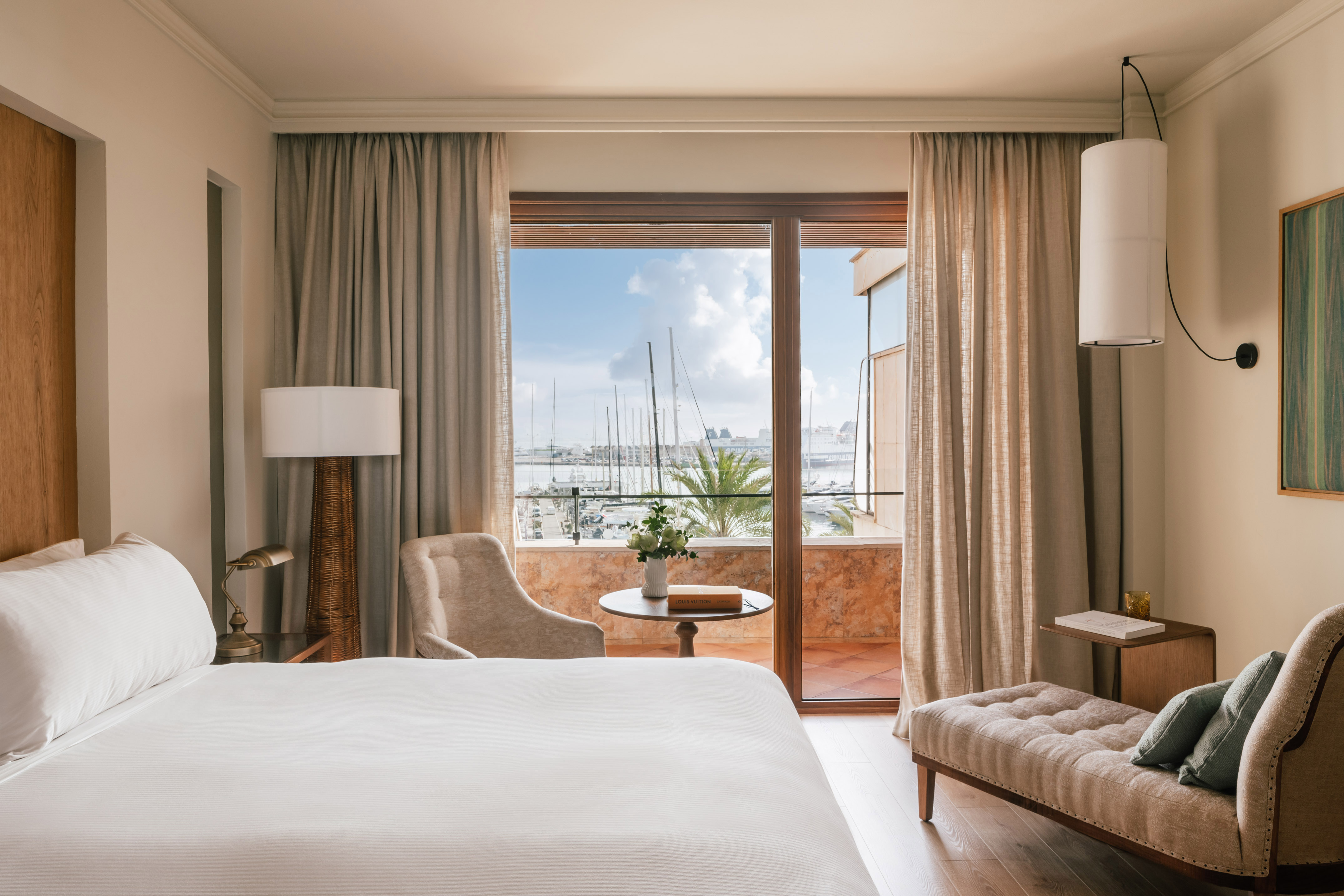 Elegant hotel room with waterfront marina view balcony.