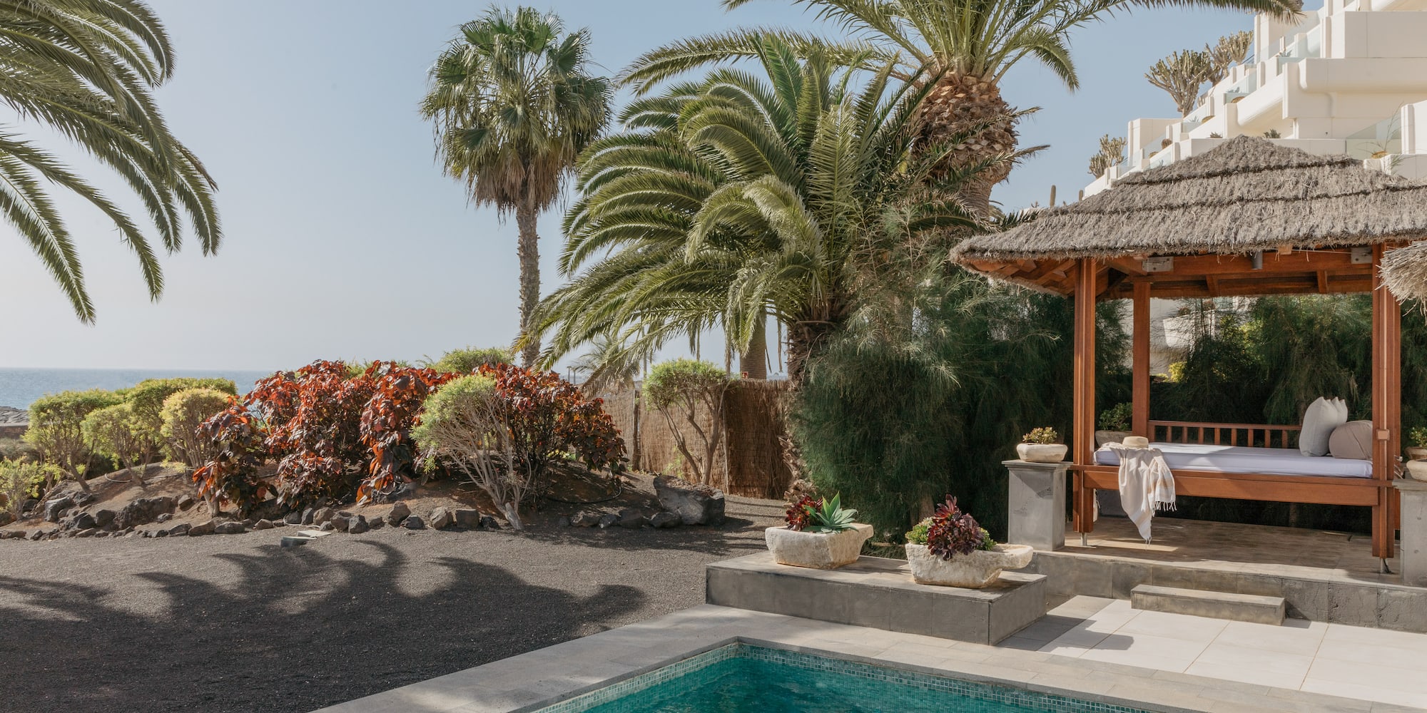 a pool with a gazebo and palm trees