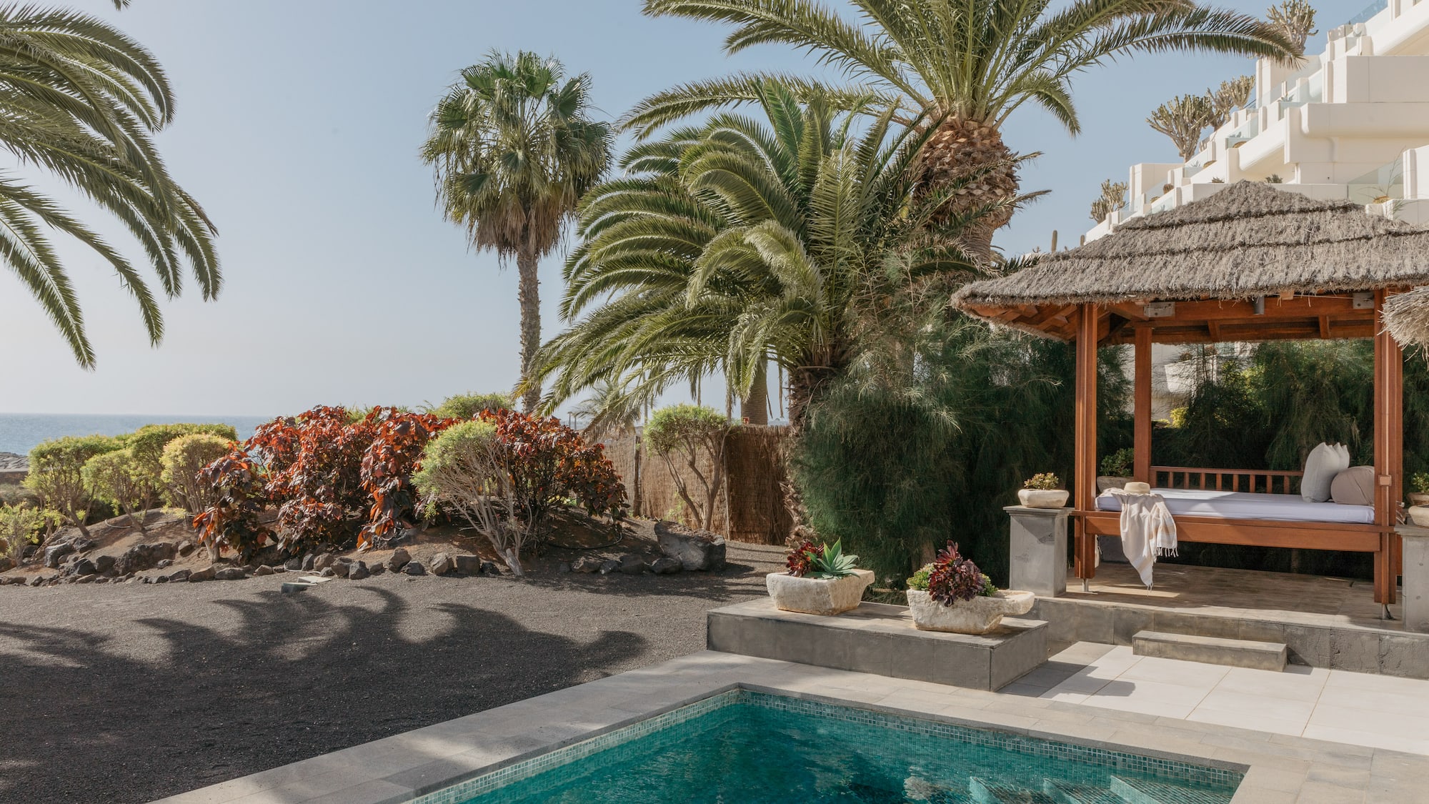 a pool with a gazebo and palm trees