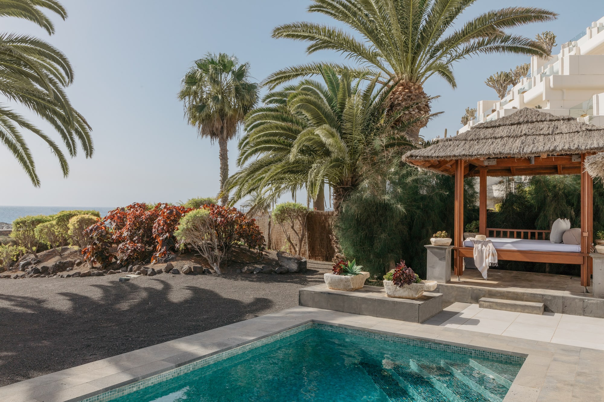a pool with a gazebo and palm trees