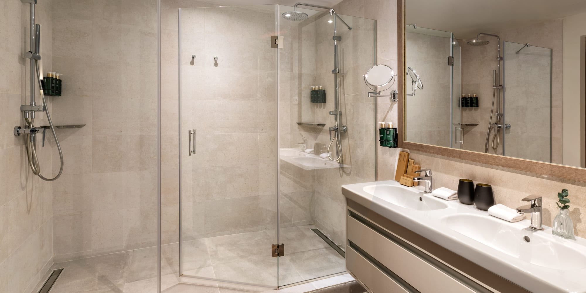 Sleek hotel bathroom with glass walk-in shower and dual sinks.