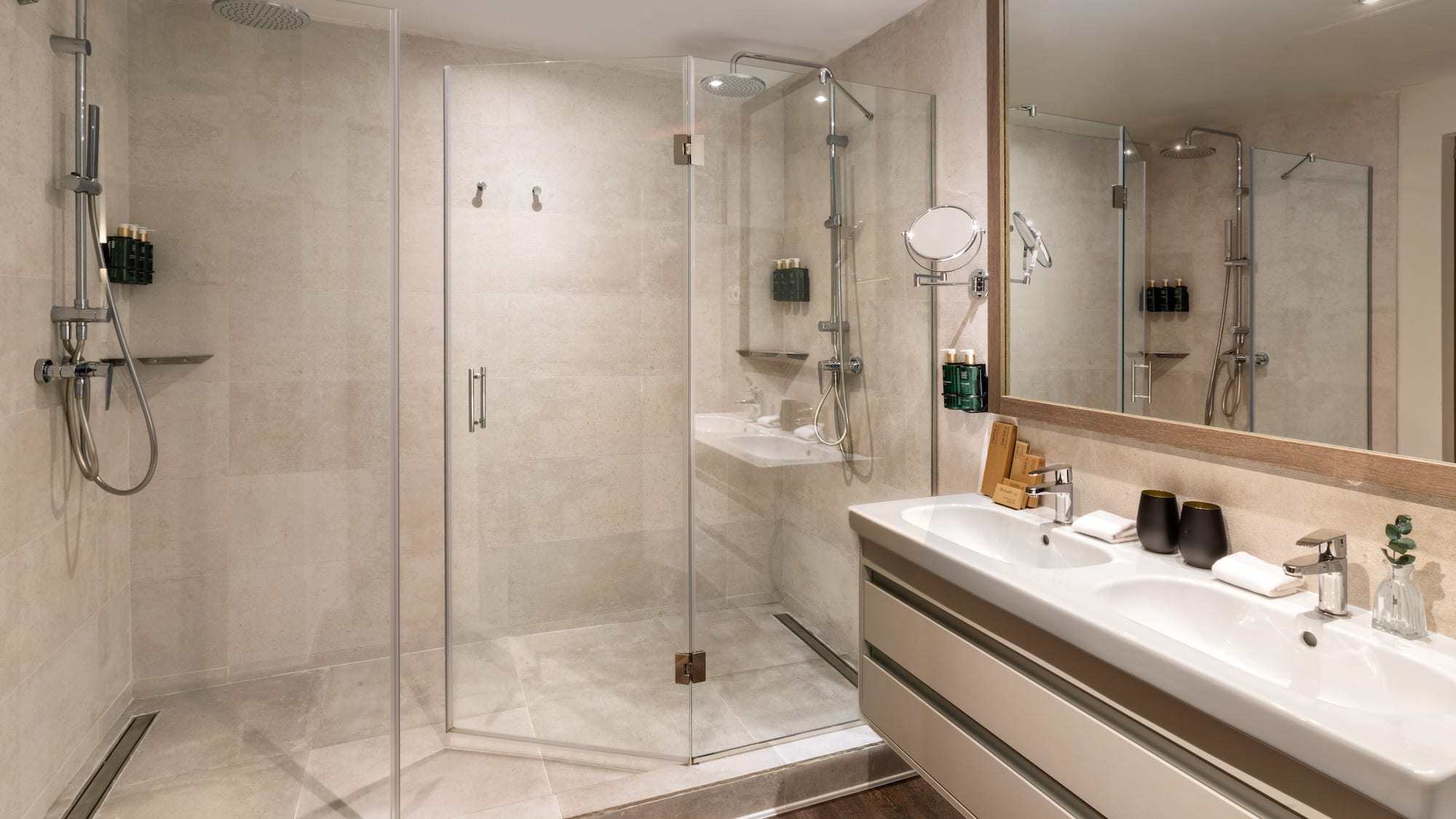 Sleek hotel bathroom with glass walk-in shower and dual sinks.