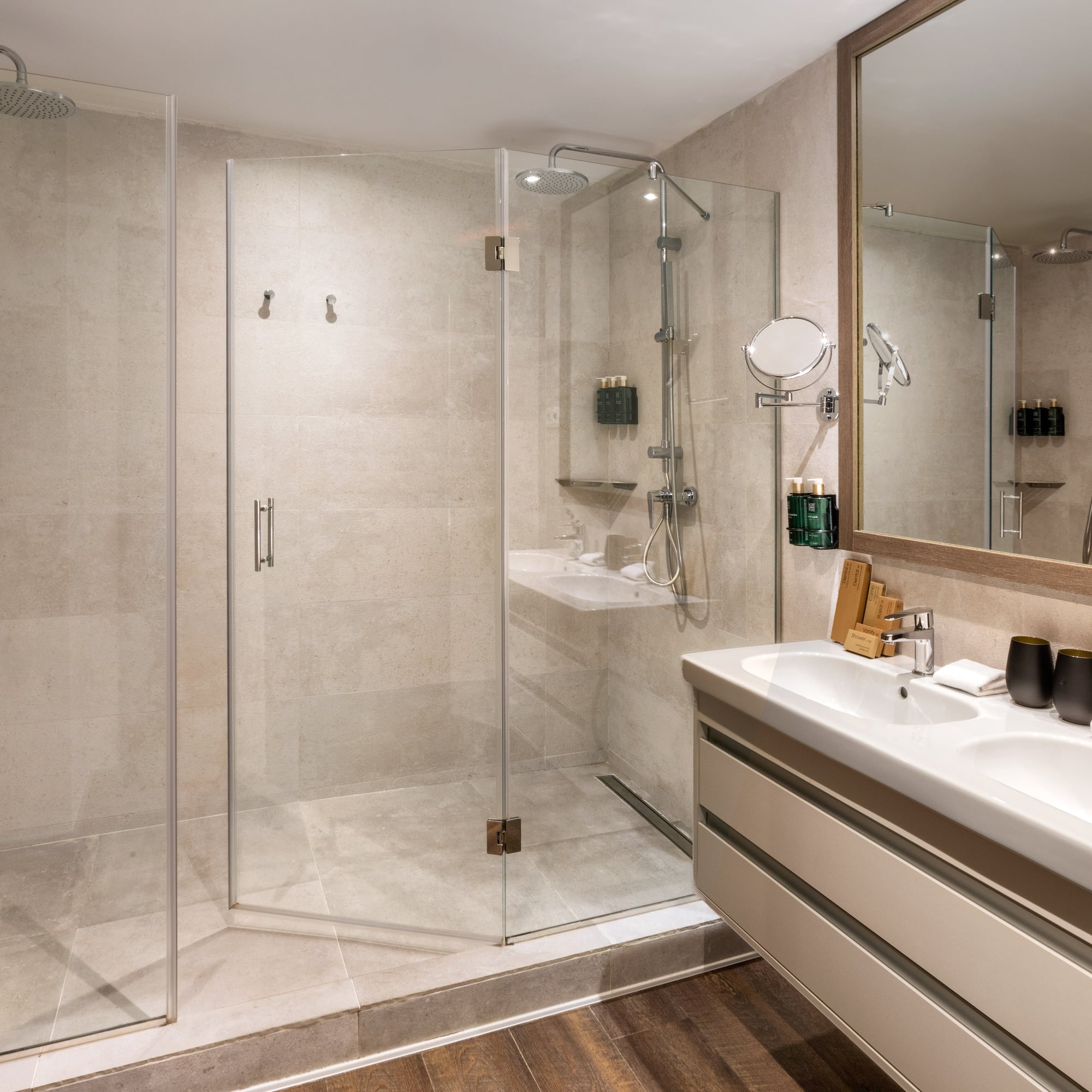 Sleek hotel bathroom with glass walk-in shower and dual sinks.