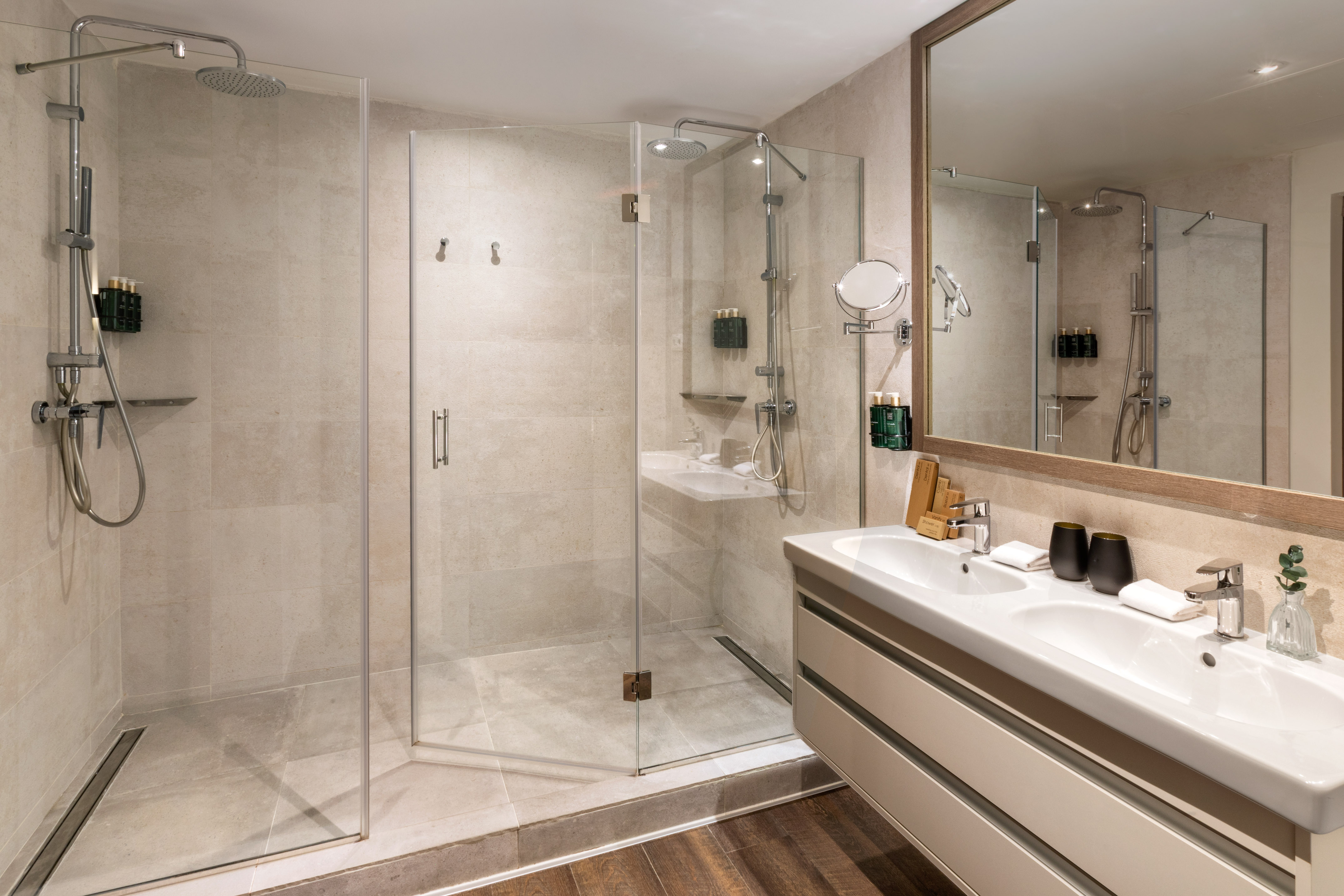 Sleek hotel bathroom with glass walk-in shower and dual sinks.