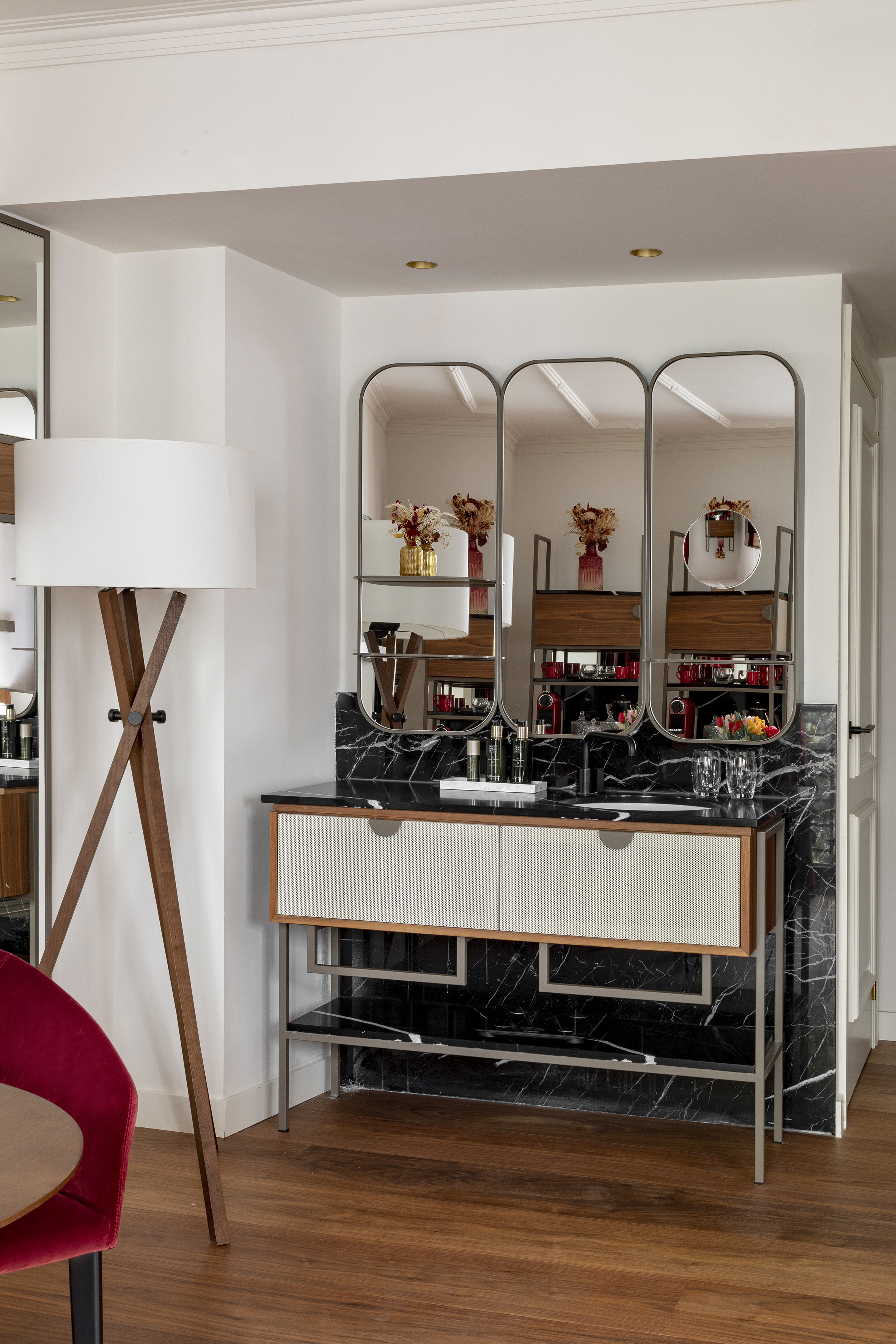 Modern hotel vanity/minibar with black marble, arched mirrors, and wood cabinetry.