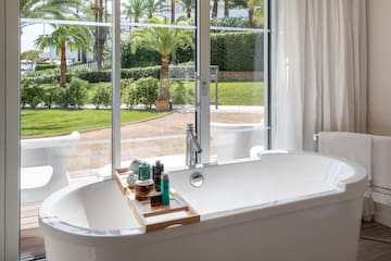 a bathtub with a tray of cosmetics and a tub outside