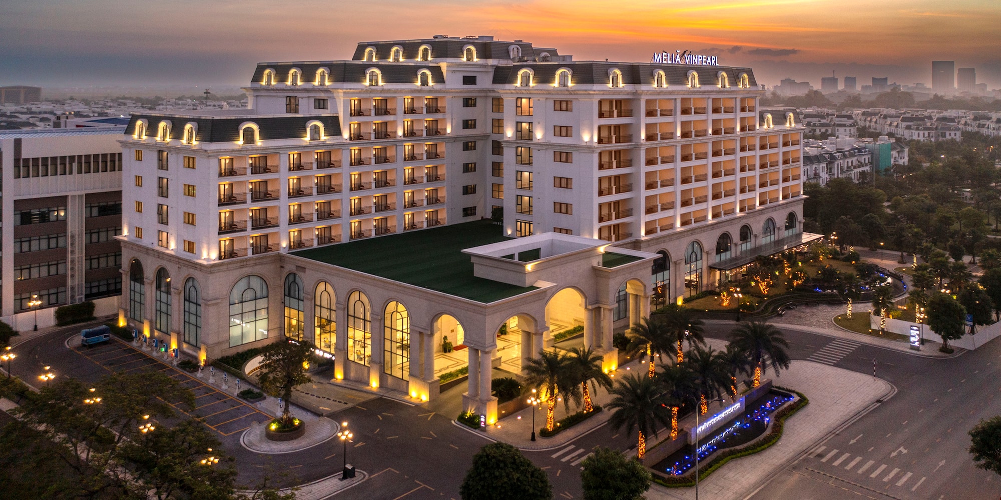 tòa nhà rộng lớn màu trắng có hàng cọ