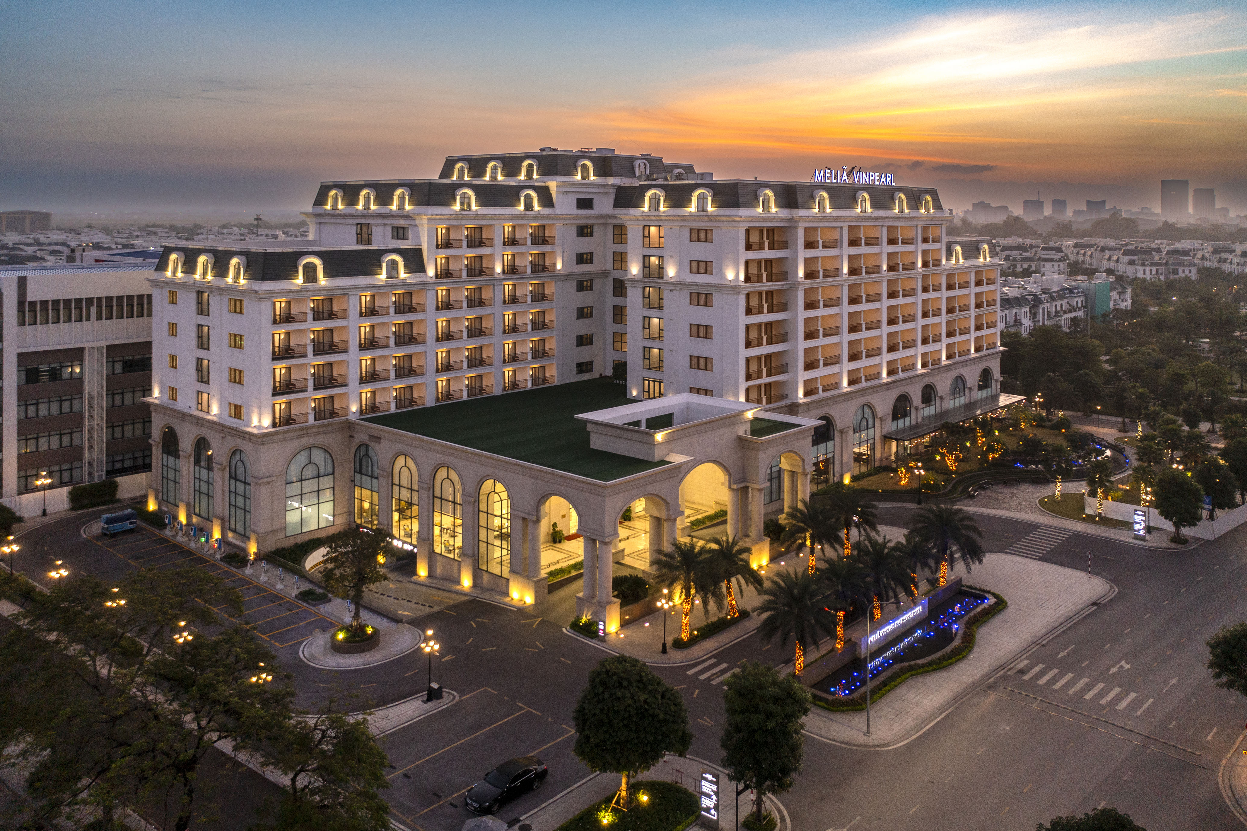 Melia Vinpearl hotel exterior at sunset with illuminated facade and palm trees.