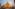 Golden Buddhist stupa wrapped in orange fabric under a hazy sun.