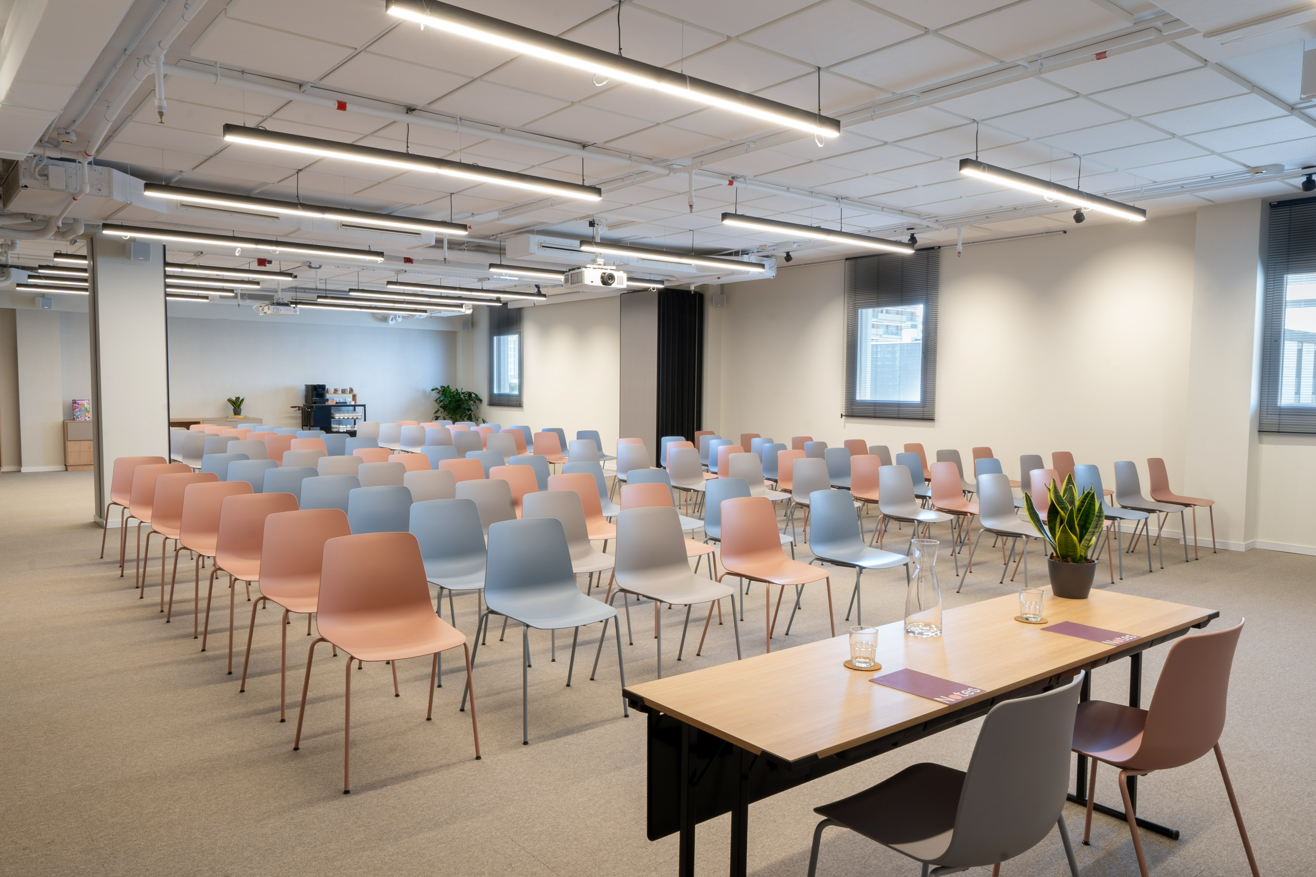 Modern conference room with pastel chairs, projector, and a presentation table.
