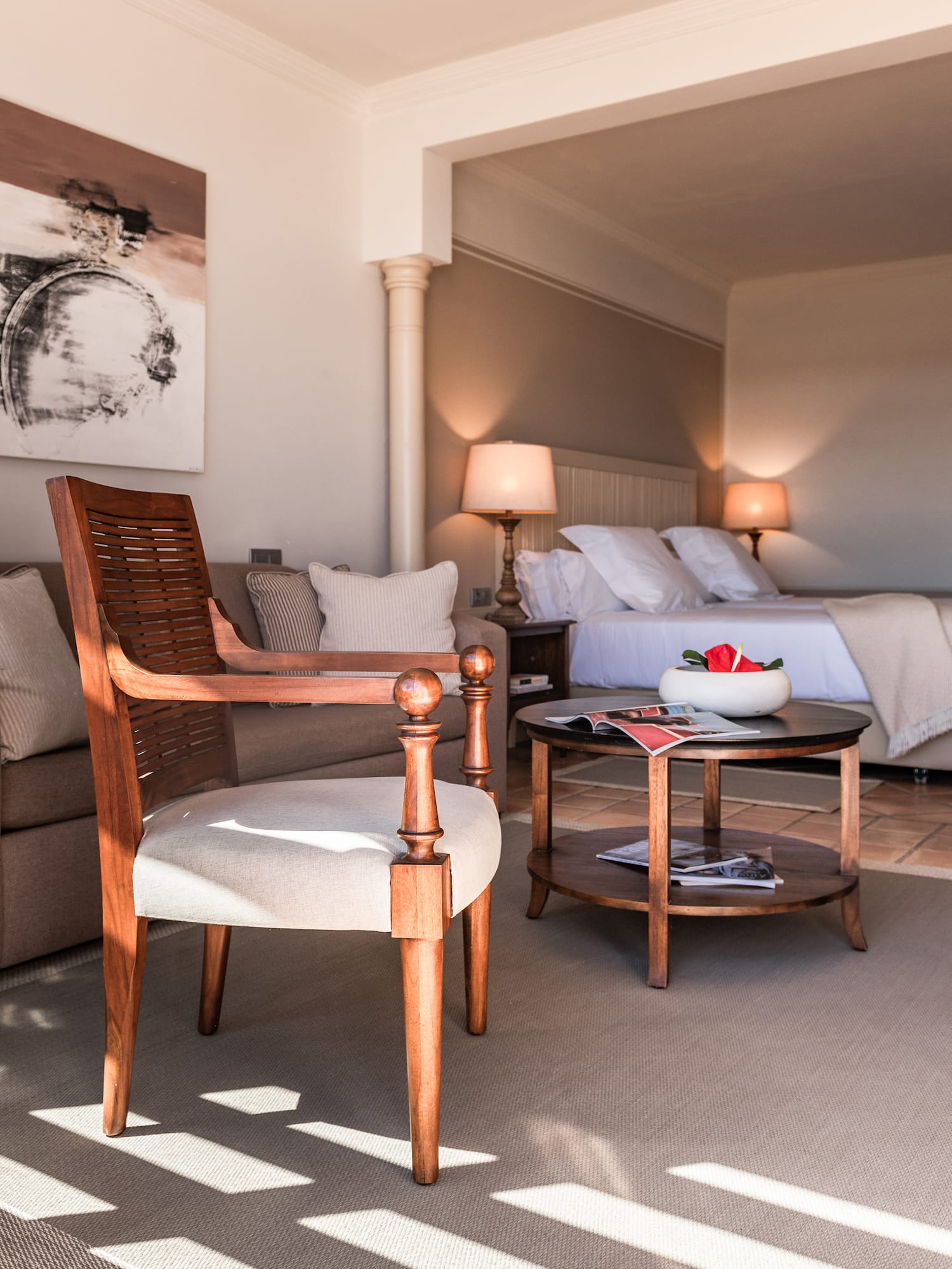 Luxury hotel suite interior with armchair, coffee table, and bedroom view.