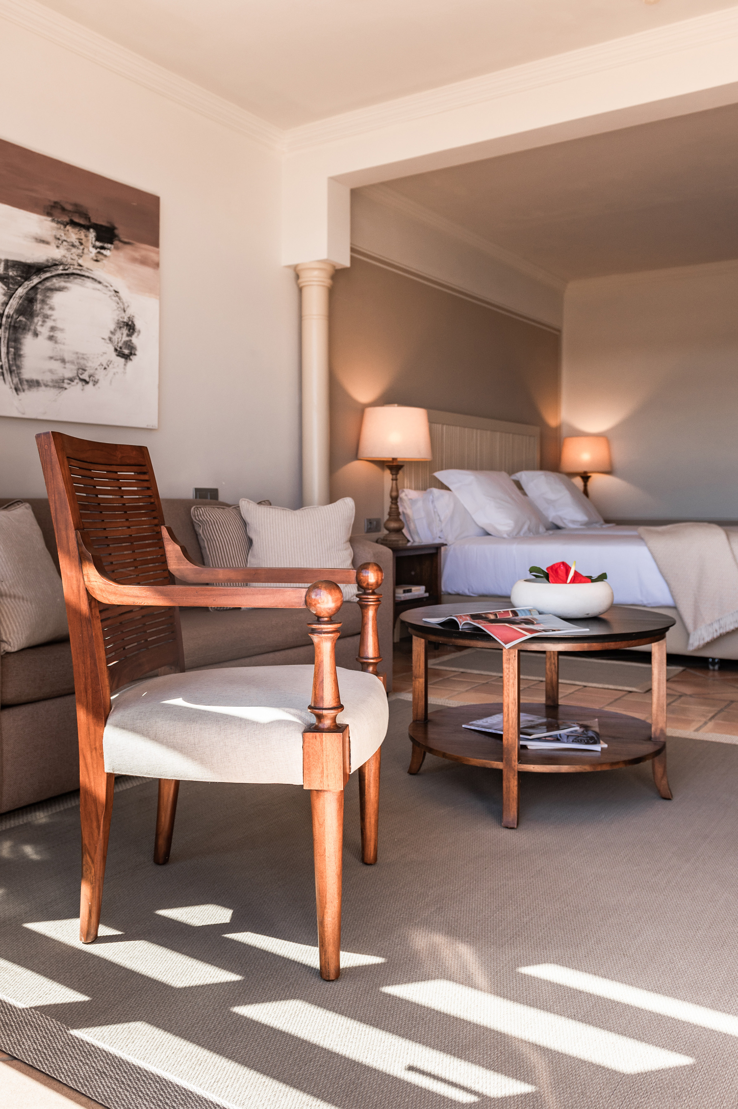 Luxury hotel suite interior with armchair, coffee table, and bedroom view.