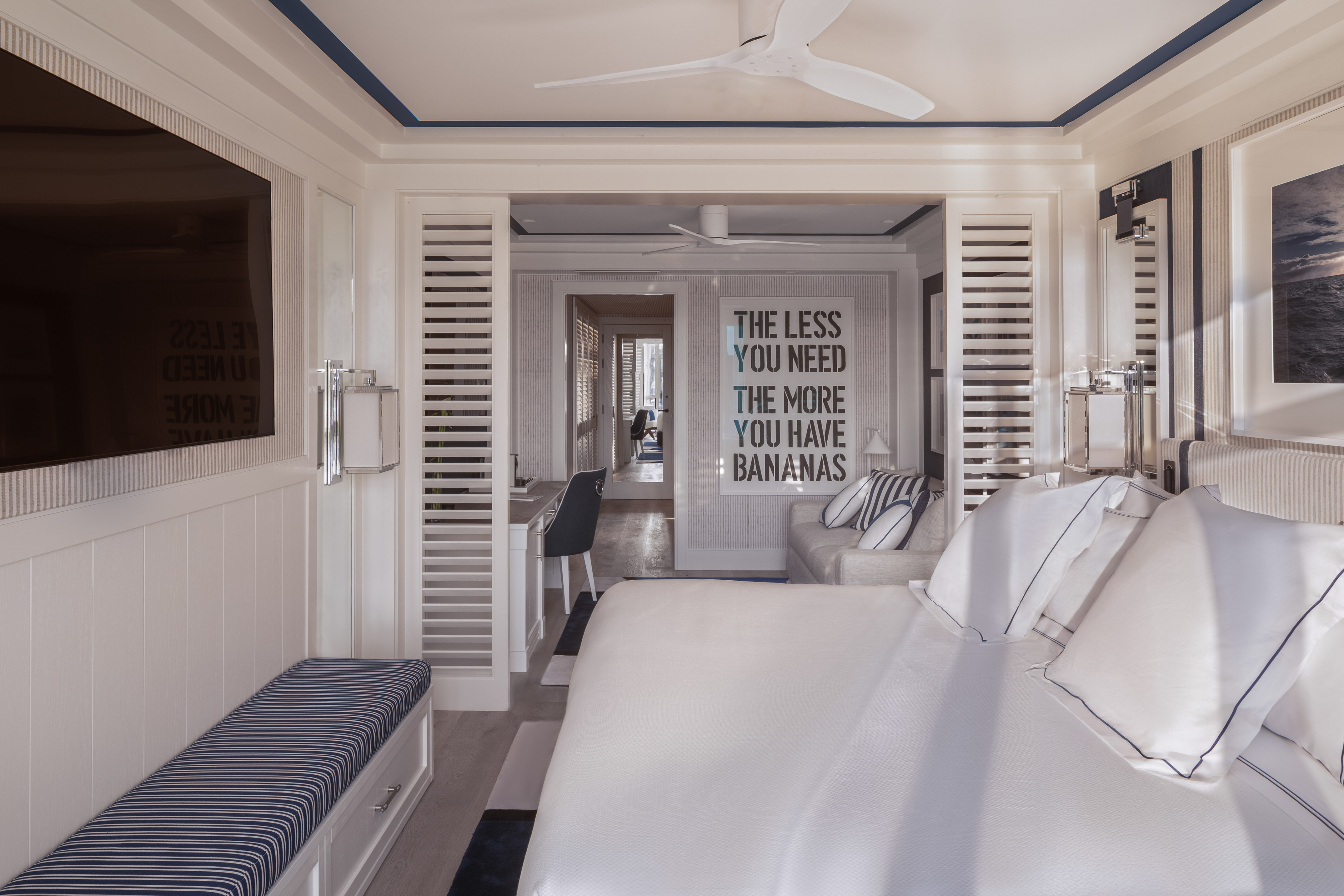 White and blue modern bedroom suite with king bed, TV, and lounge area.