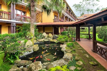 a pond with fish in it surrounded by trees and Jim Thompson House
