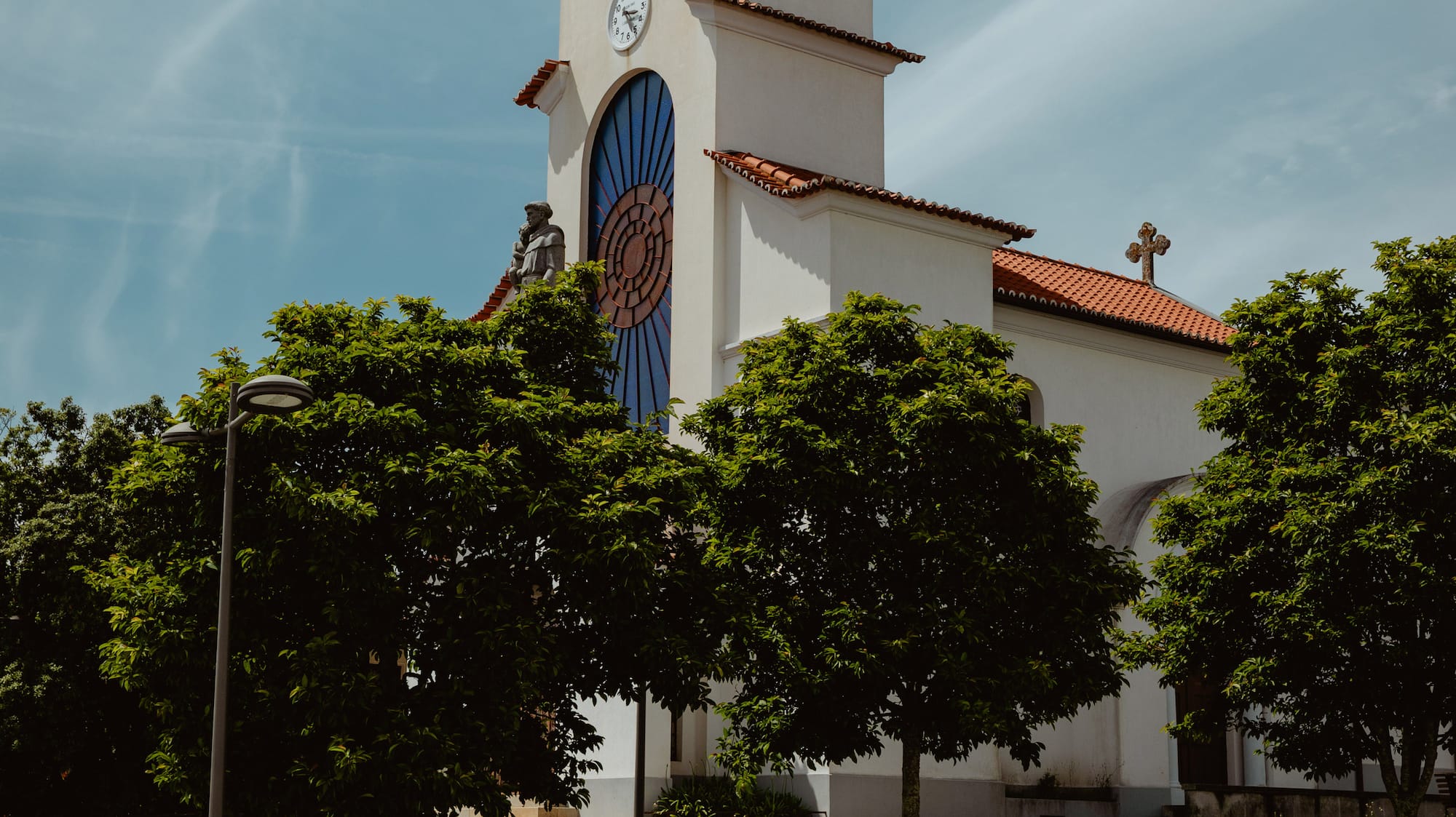 a white church with a clock tower and trees
