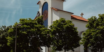 a white church with a clock tower and trees