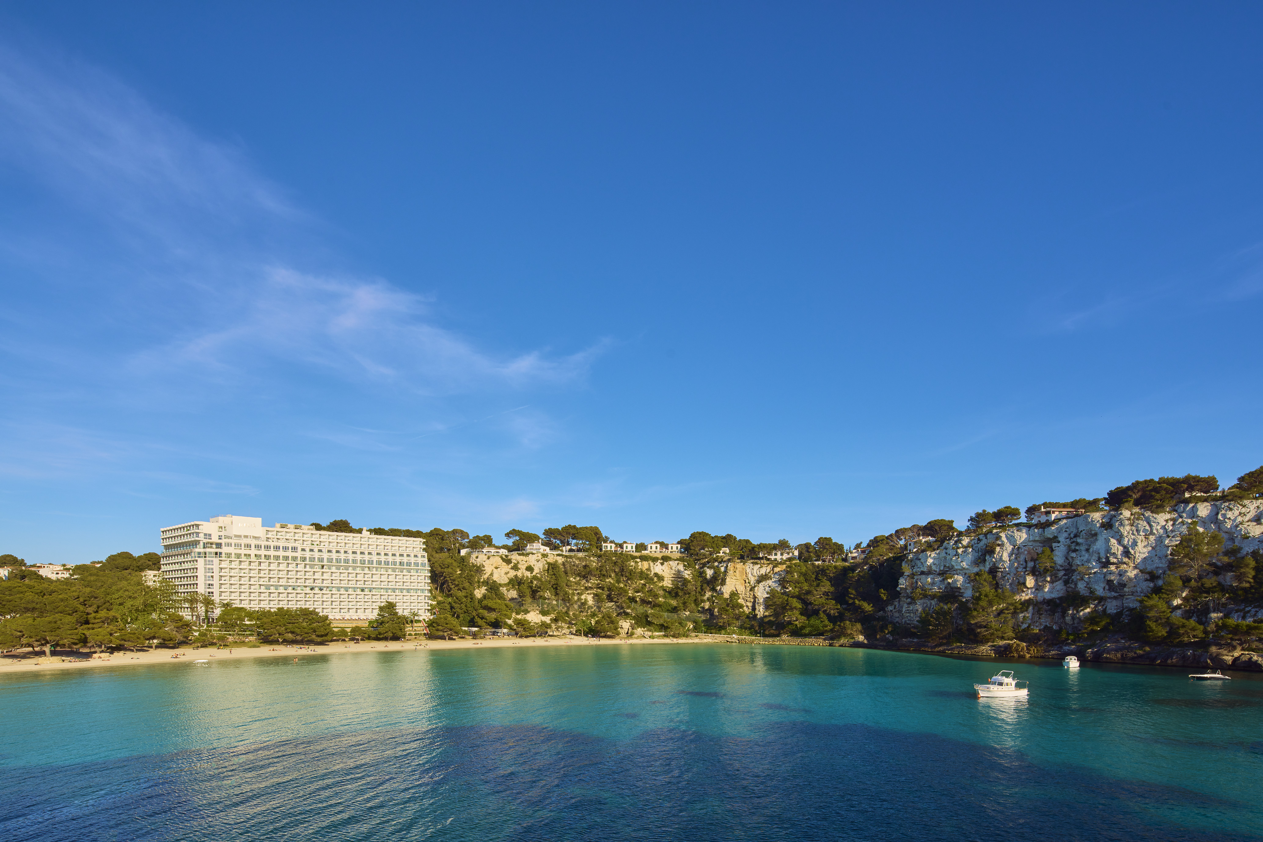 Cala Galdana bay, Menorca: beachfront hotel, sandy beach, turquoise sea, boats.