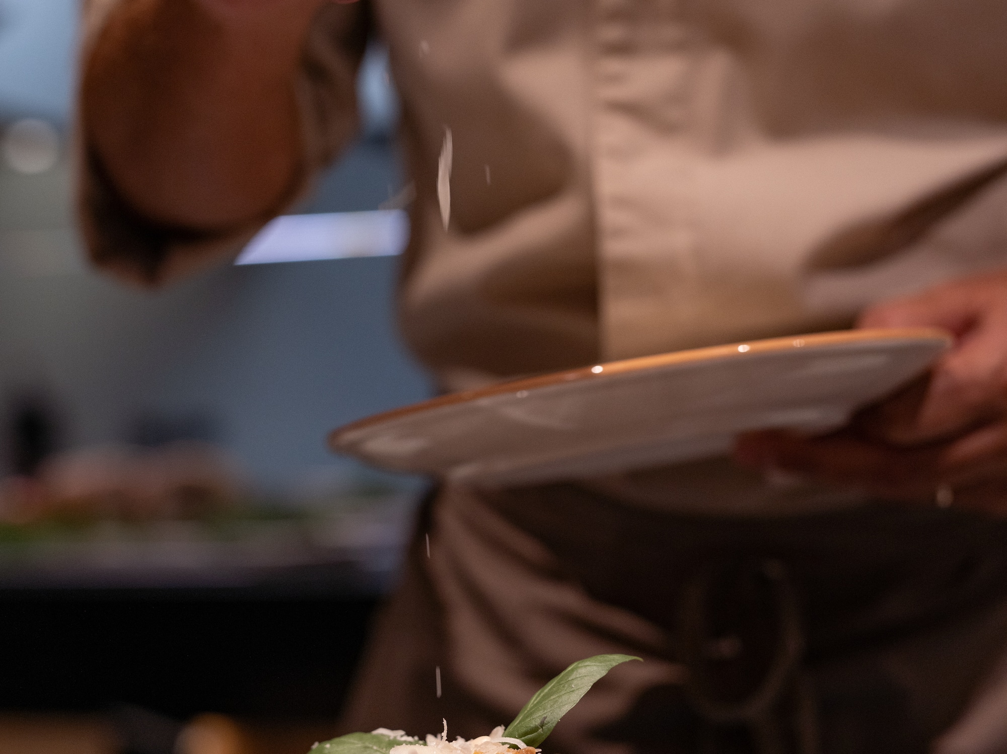a person sprinkling salt on a plate of food