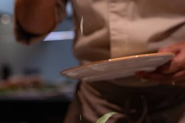 a person sprinkling salt on a plate of food