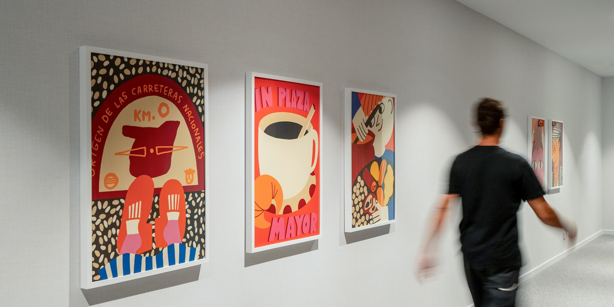 a man walking past a wall with art on it