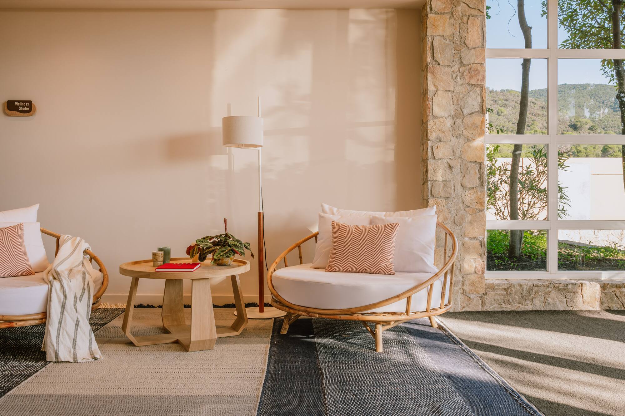 Wellness Studio with rattan chairs, wooden side table, and large window to nature.