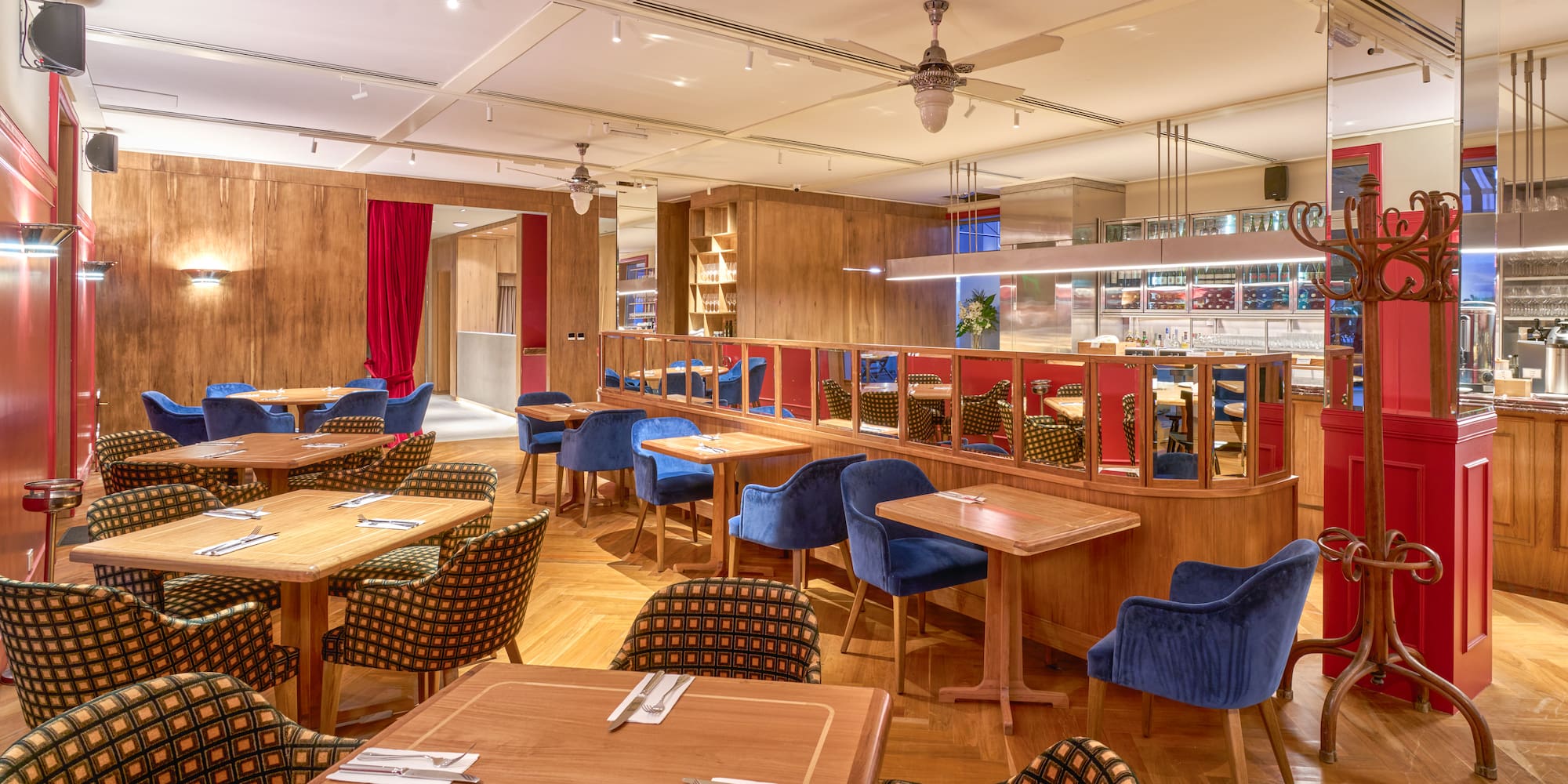 Stylish restaurant dining room with wooden tables, blue velvet and patterned chairs.