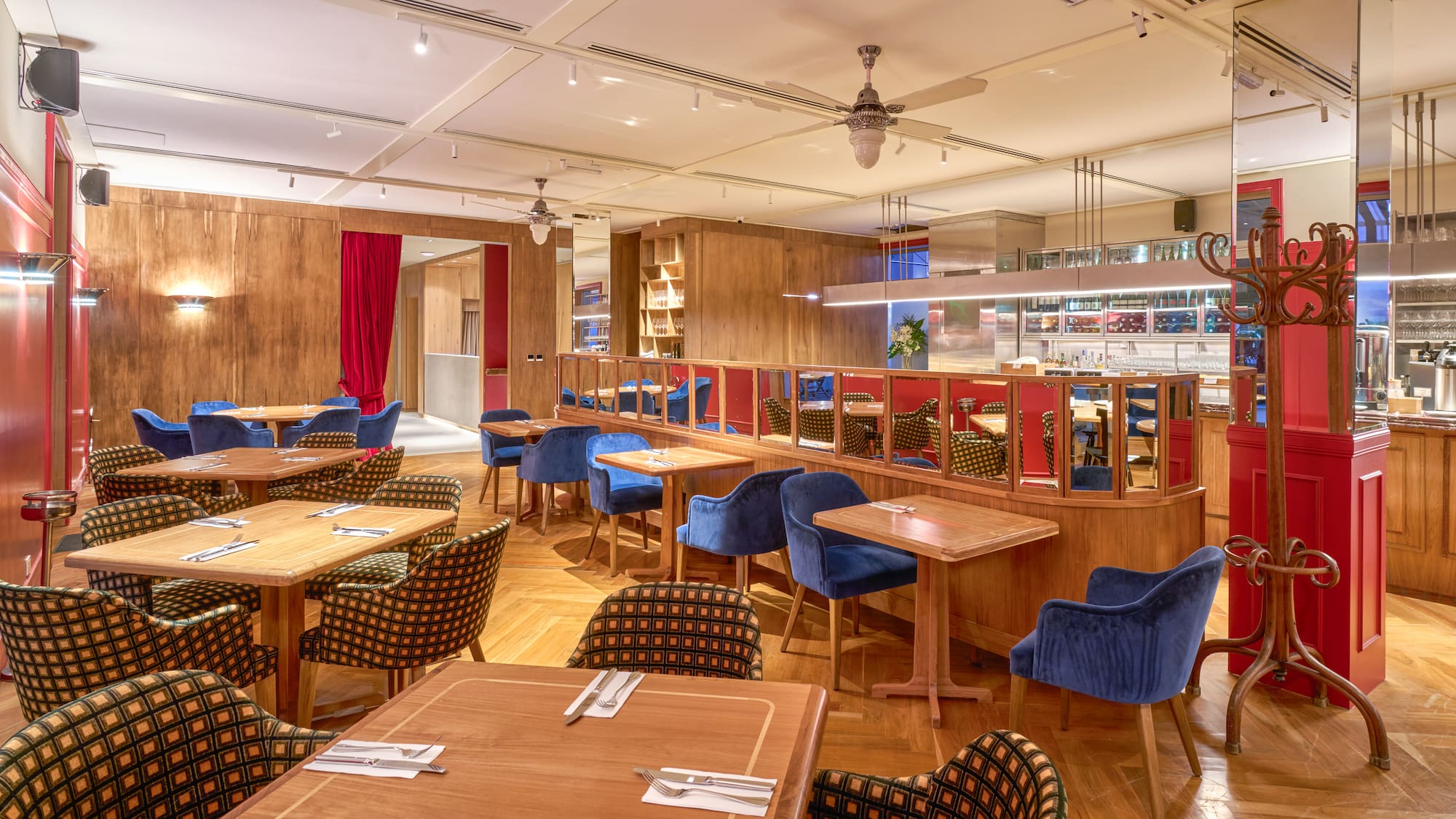 Stylish restaurant dining room with wooden tables, blue velvet and patterned chairs.