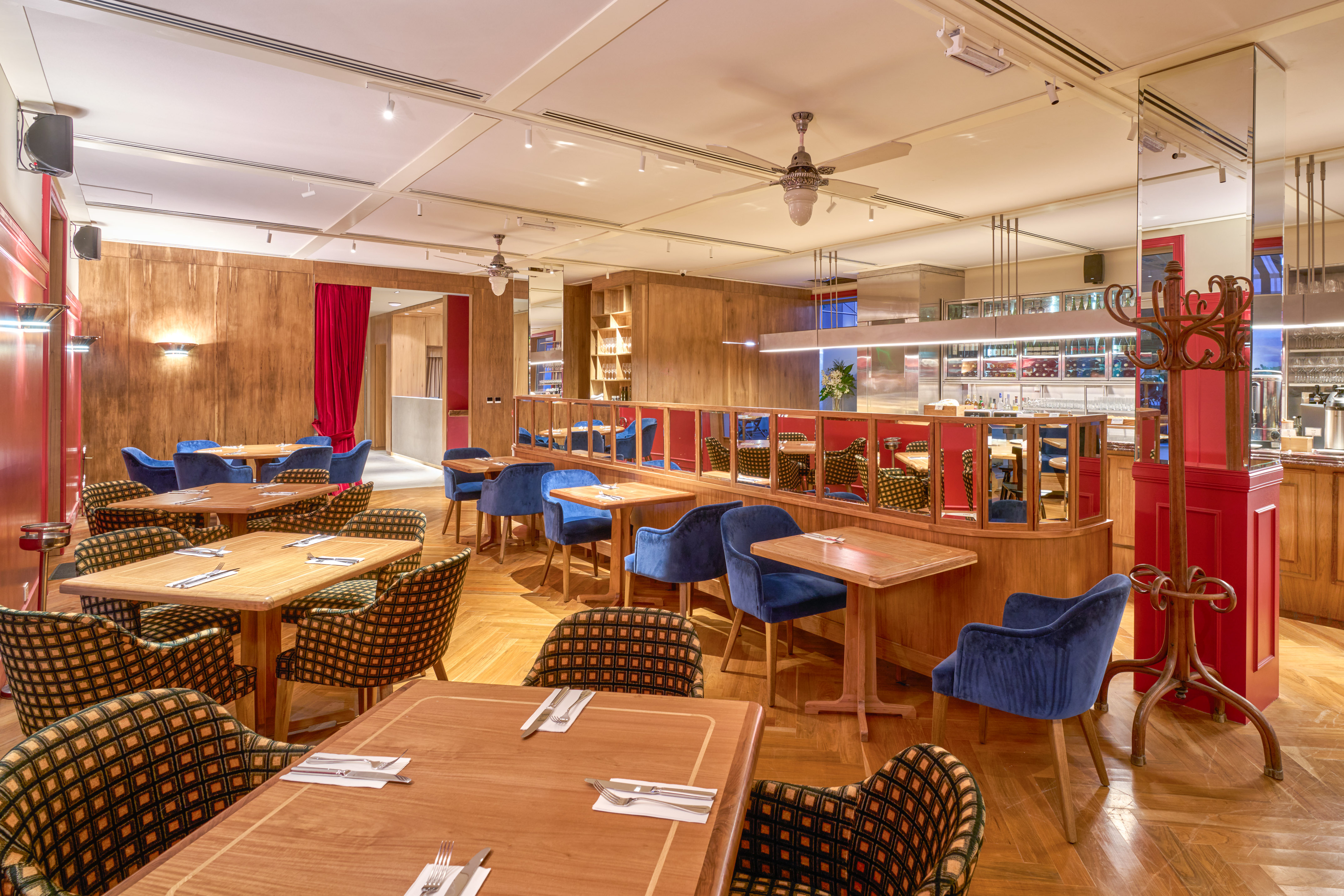 Stylish restaurant dining room with wooden tables, blue velvet and patterned chairs.