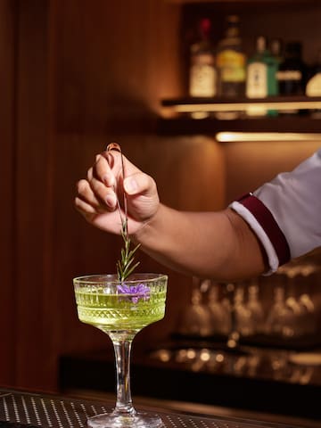 a person holding a stem of a plant in a glass
