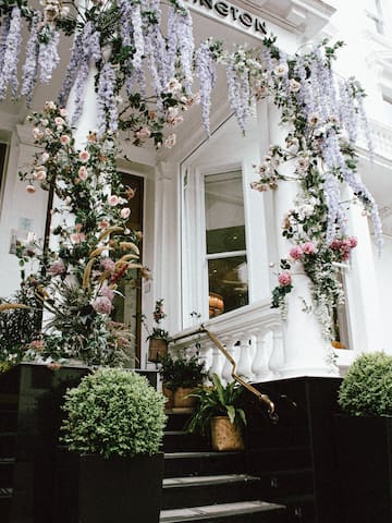 a white building with a white column and a white staircase with flowers
