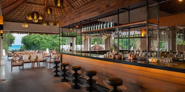 a bar with stools and bottles of alcohol