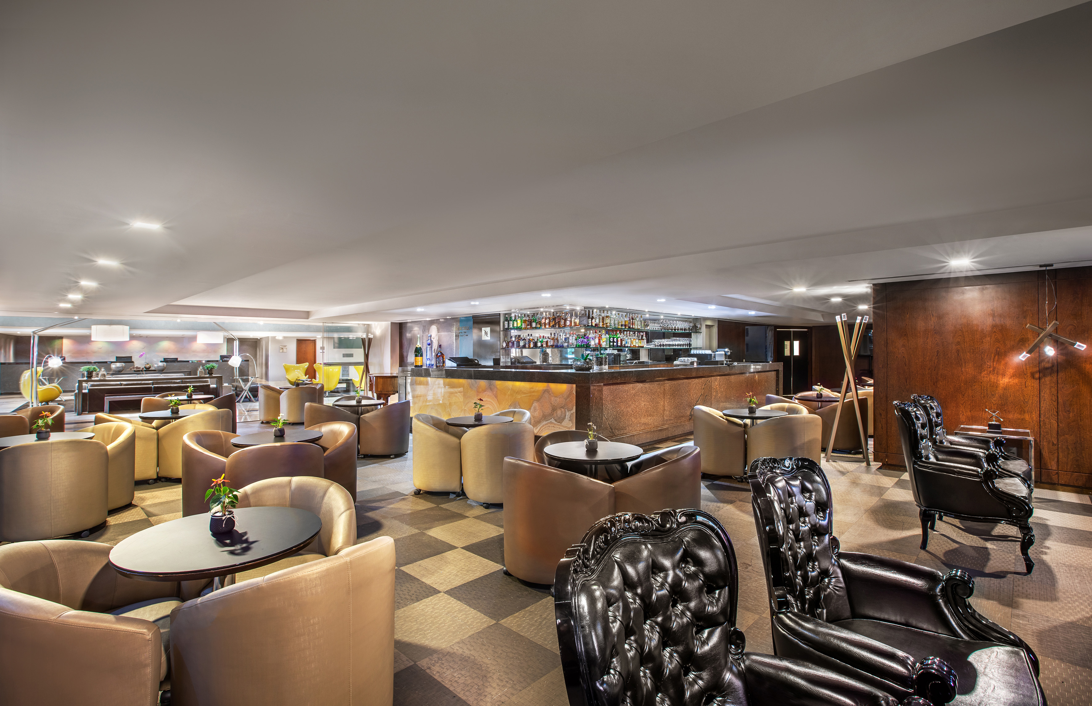 Hotel lobby bar with comfortable chairs, small tables, and a full liquor bar.