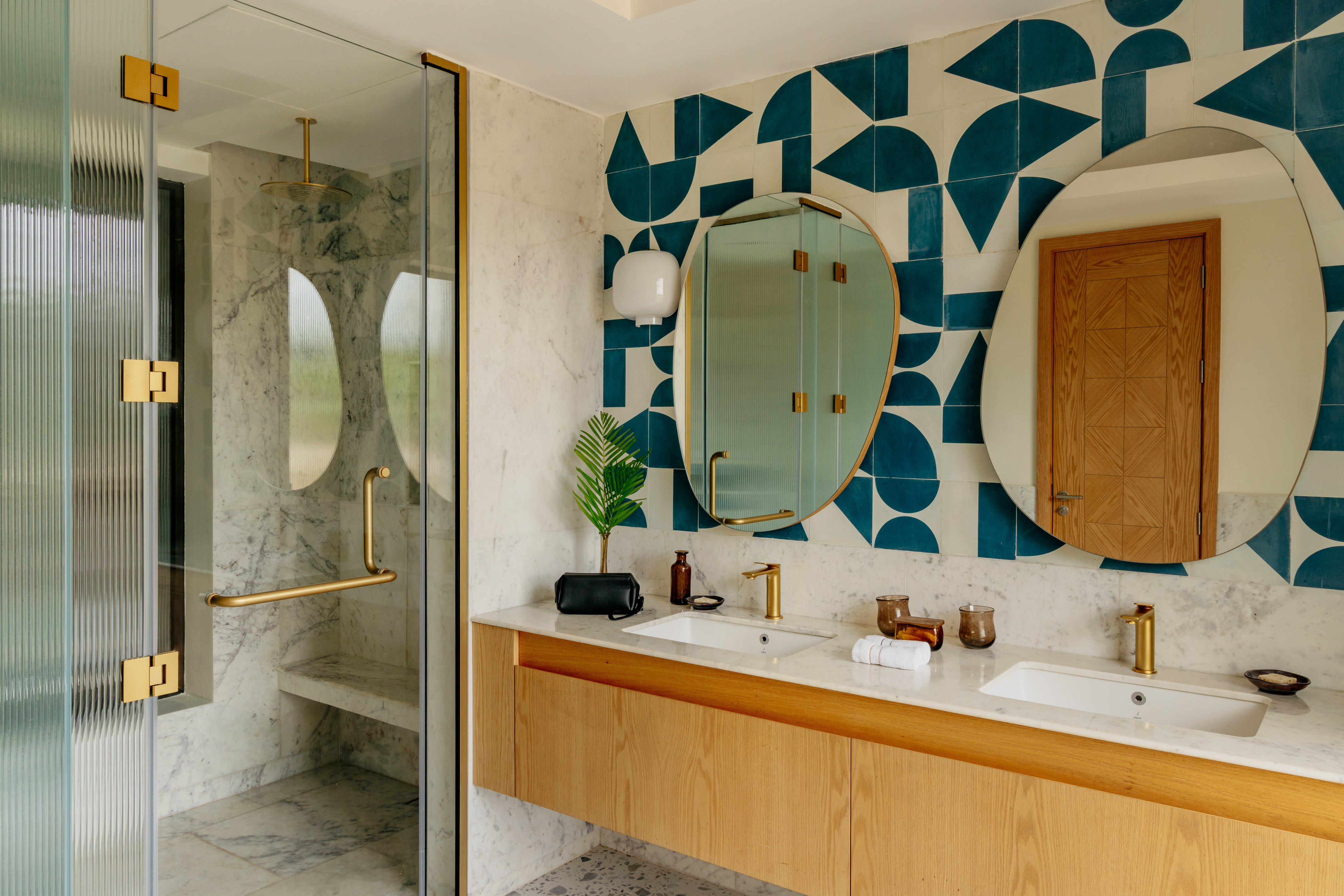 Modern bathroom with double vanity, marble, geometric tiles, and brass fixtures.