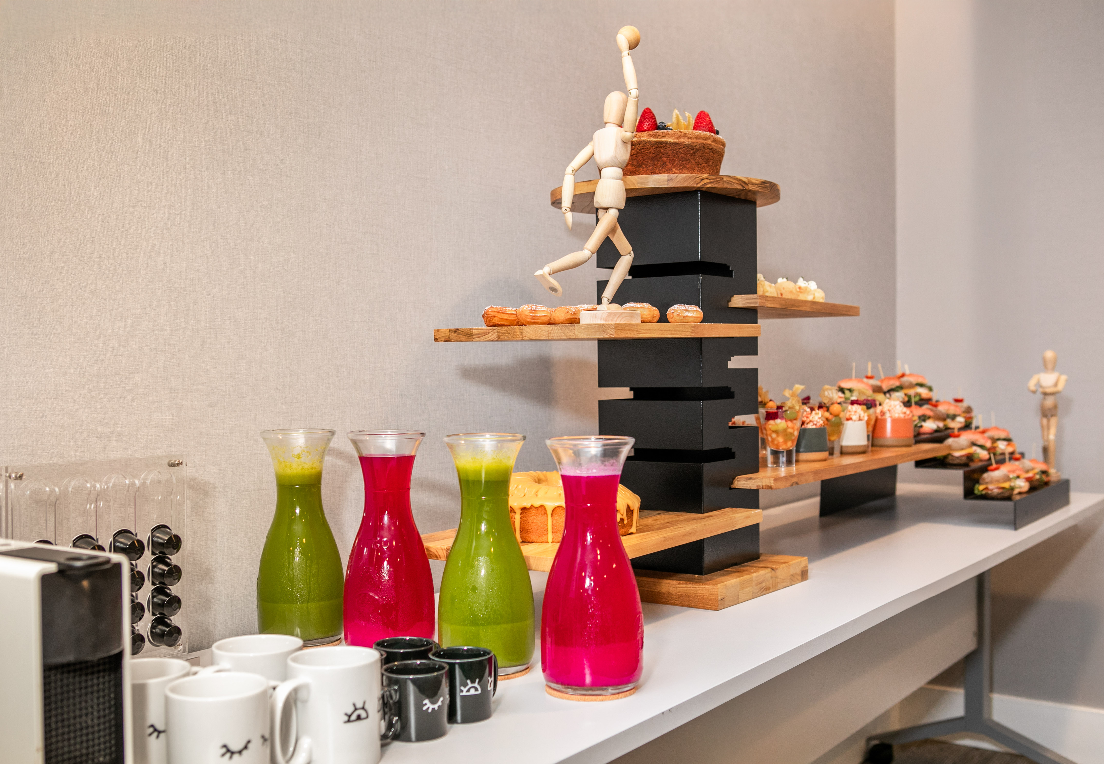 Fresh juices, pastries, and sandwiches on a modern tiered catering buffet.