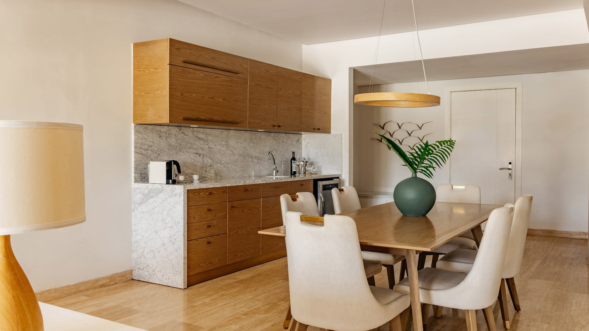 Modern kitchenette and dining area with wooden cabinets and marble counter.