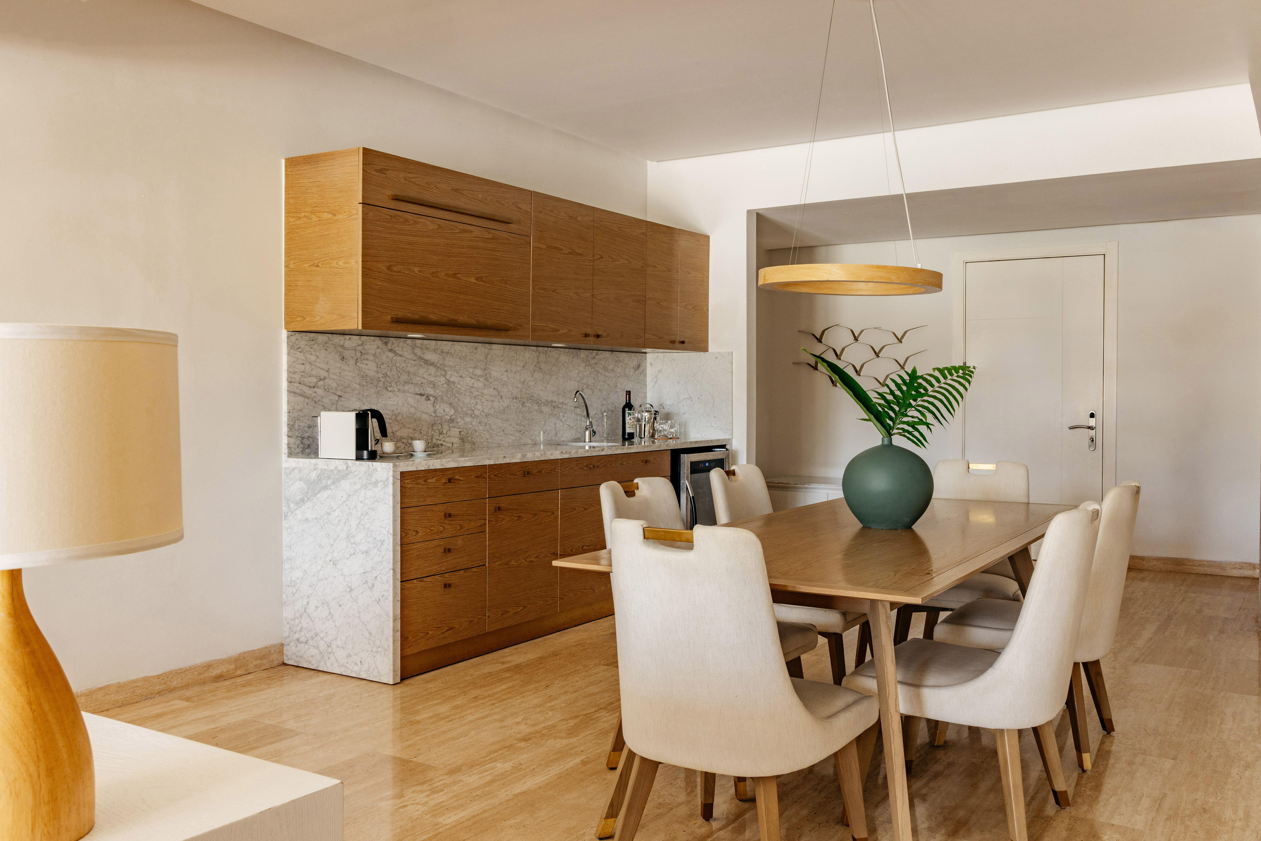 Modern kitchenette and dining area with wooden cabinets and marble counter.