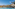 Luxury resort pool with palm trees, hotel buildings, and distant mountains.