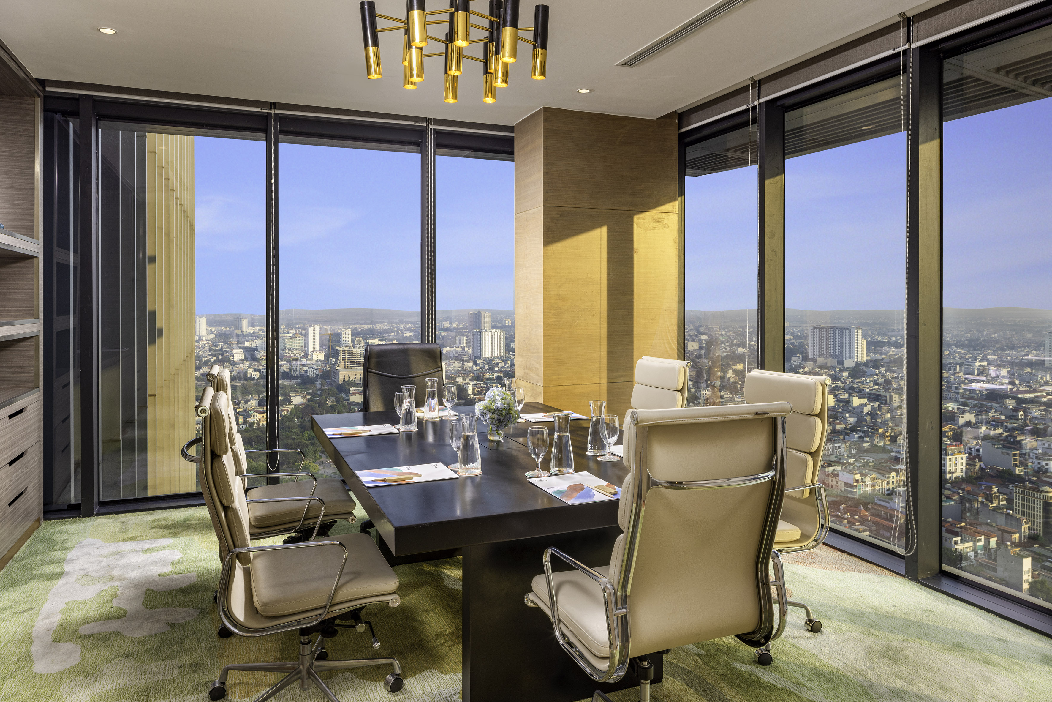 Modern conference room with panoramic city view, elegant table, and office chairs.