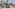 Luxury resort pool with wooden cabanas, blue daybeds, and palm trees.