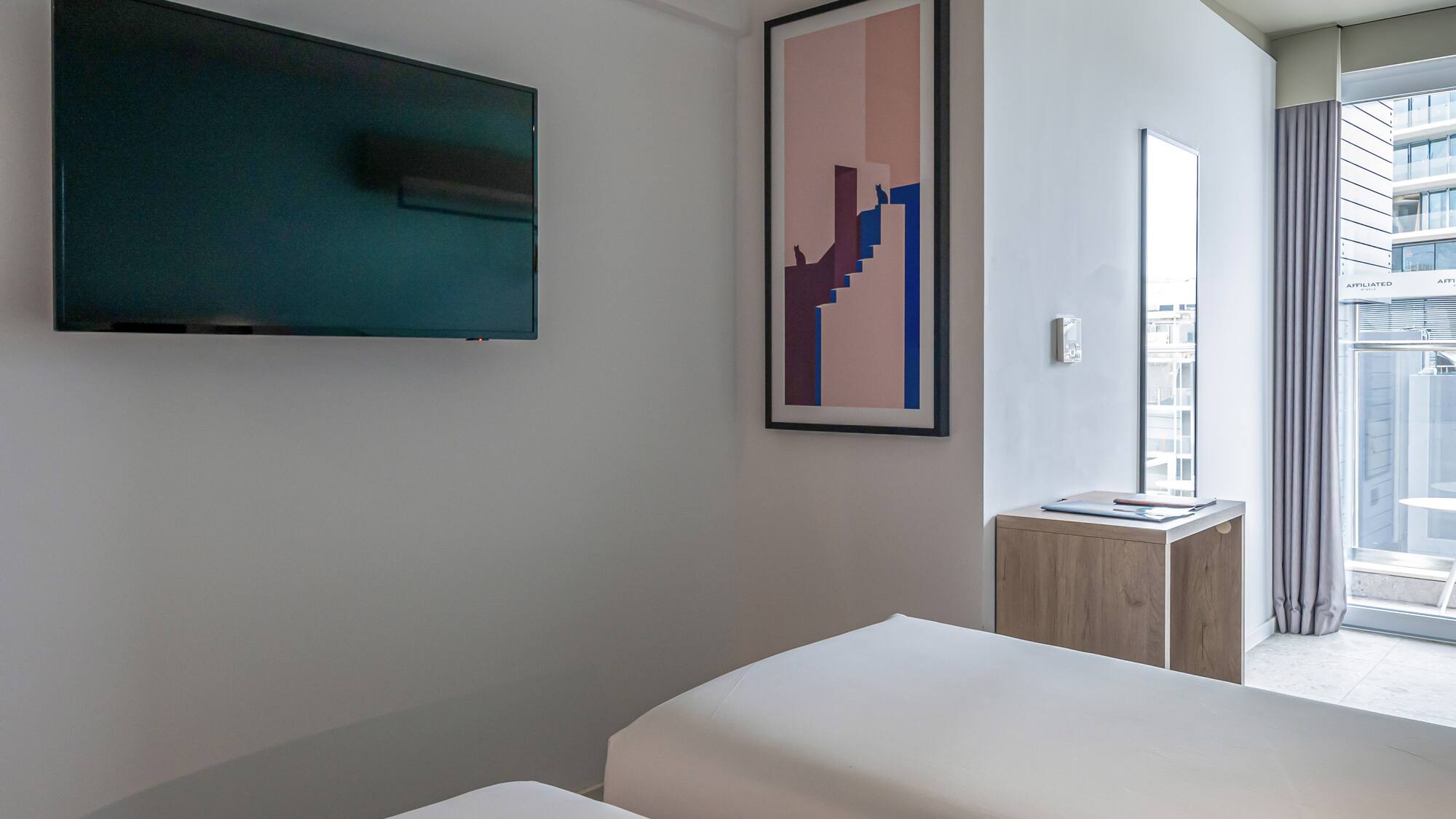 a room with two beds and a tv on the wall