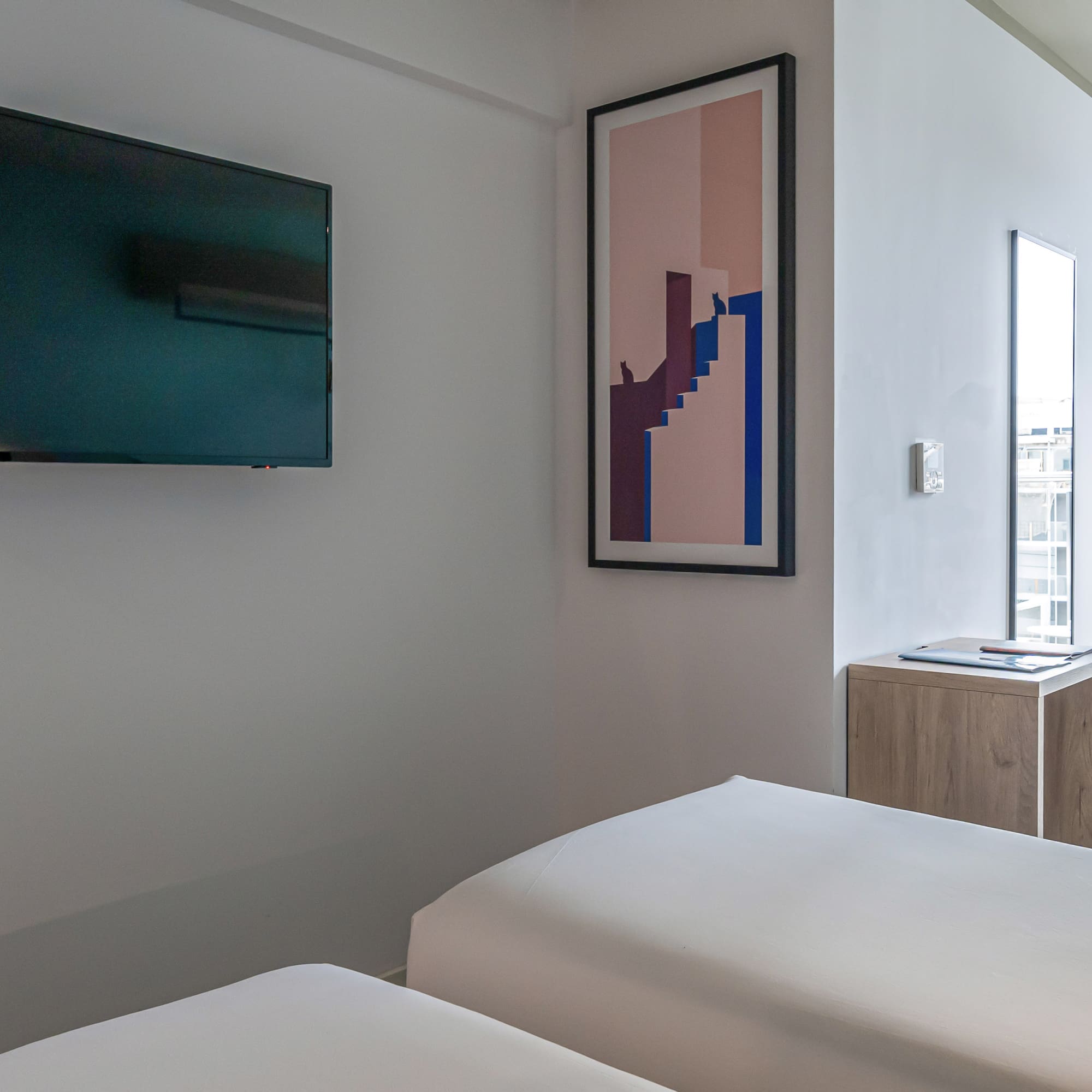 a room with two beds and a tv on the wall