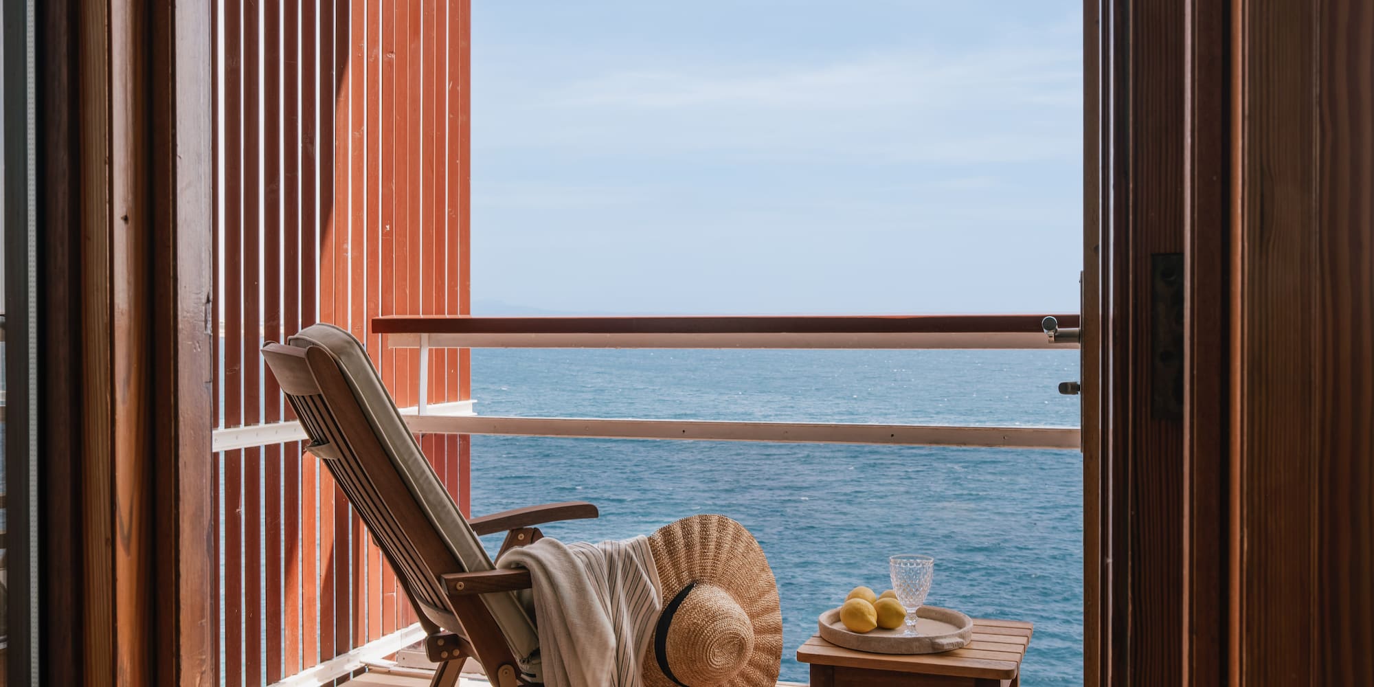 a chair and table on a balcony overlooking the ocean
