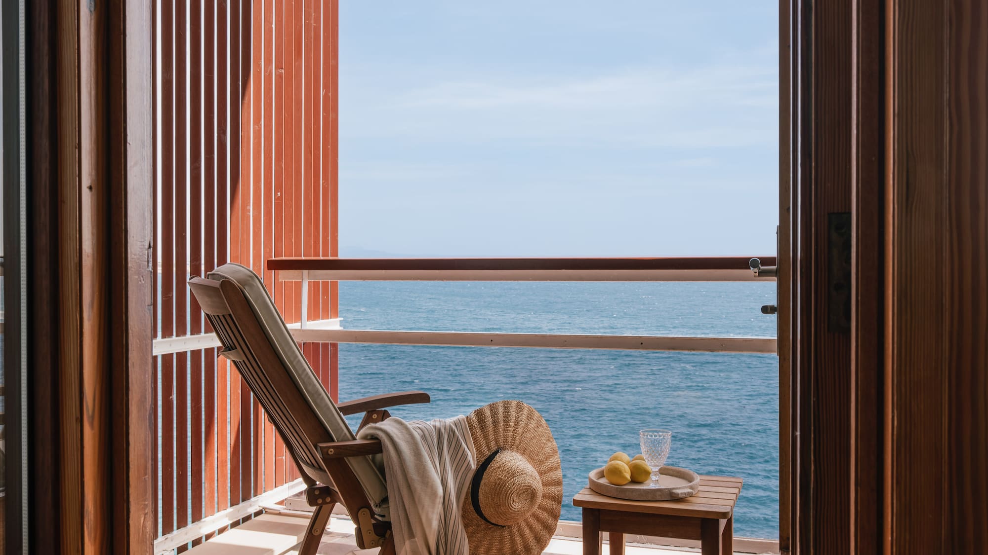 a chair and table on a balcony overlooking the ocean