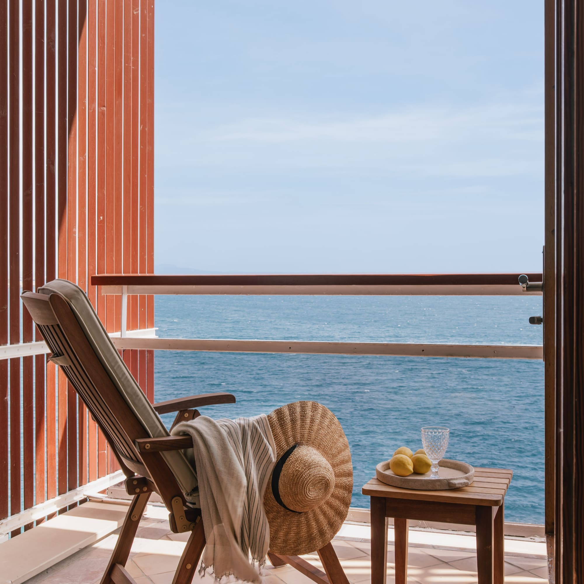 a chair and table on a balcony overlooking the ocean