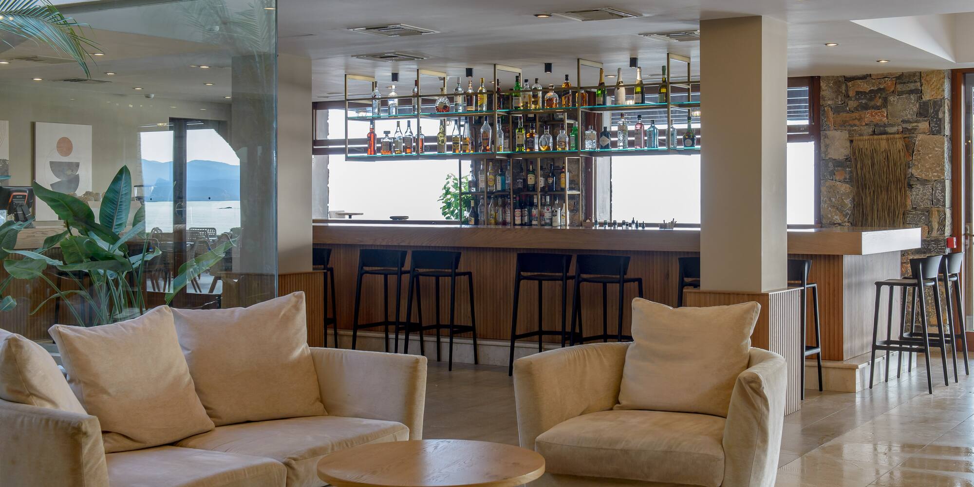 Stylish hotel lobby bar with comfortable sofas, full bar, and sea view.