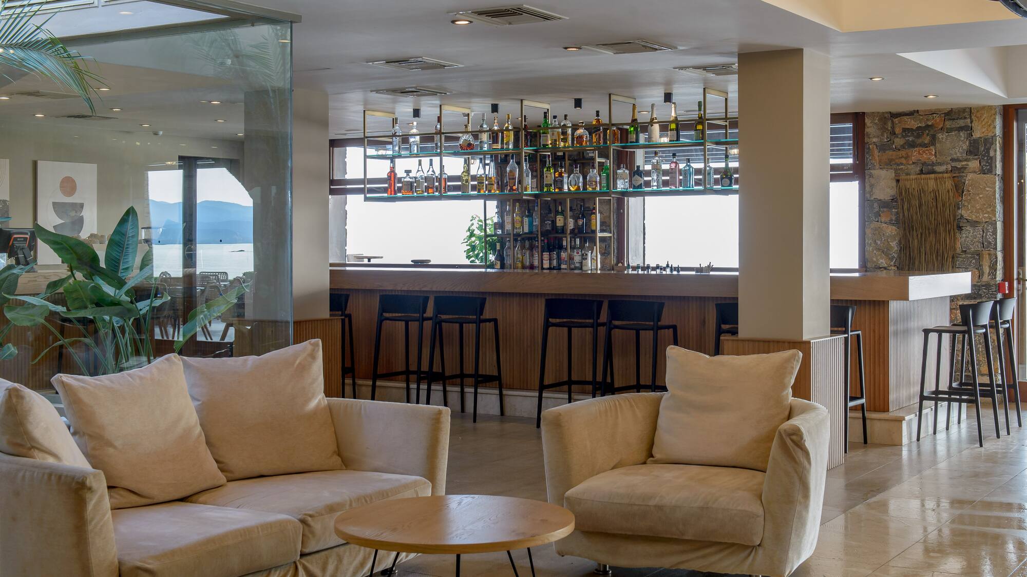 Stylish hotel lobby bar with comfortable sofas, full bar, and sea view.