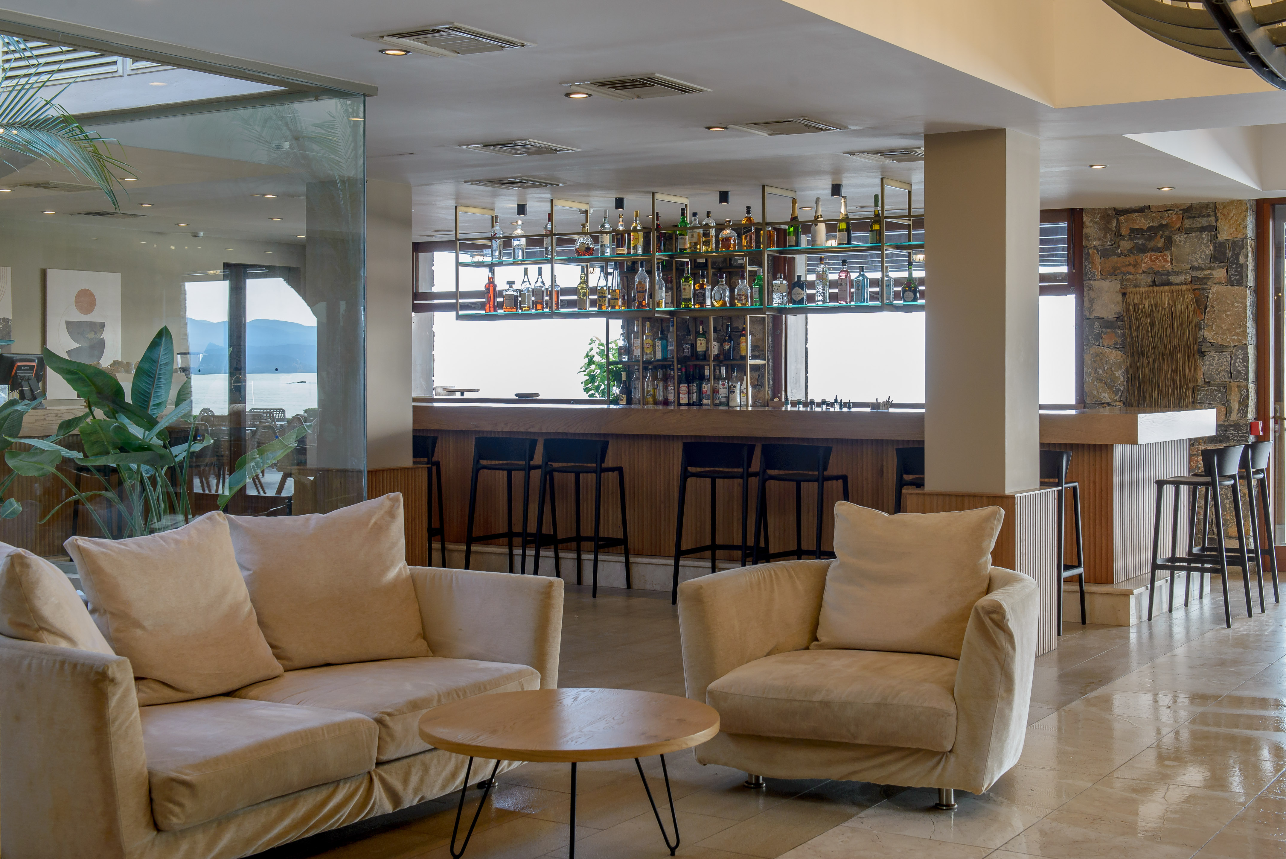 Stylish hotel lobby bar with comfortable sofas, full bar, and sea view.